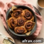 Overhead view of air fried cinnamon rolls in a round cake pan, freshly baked.