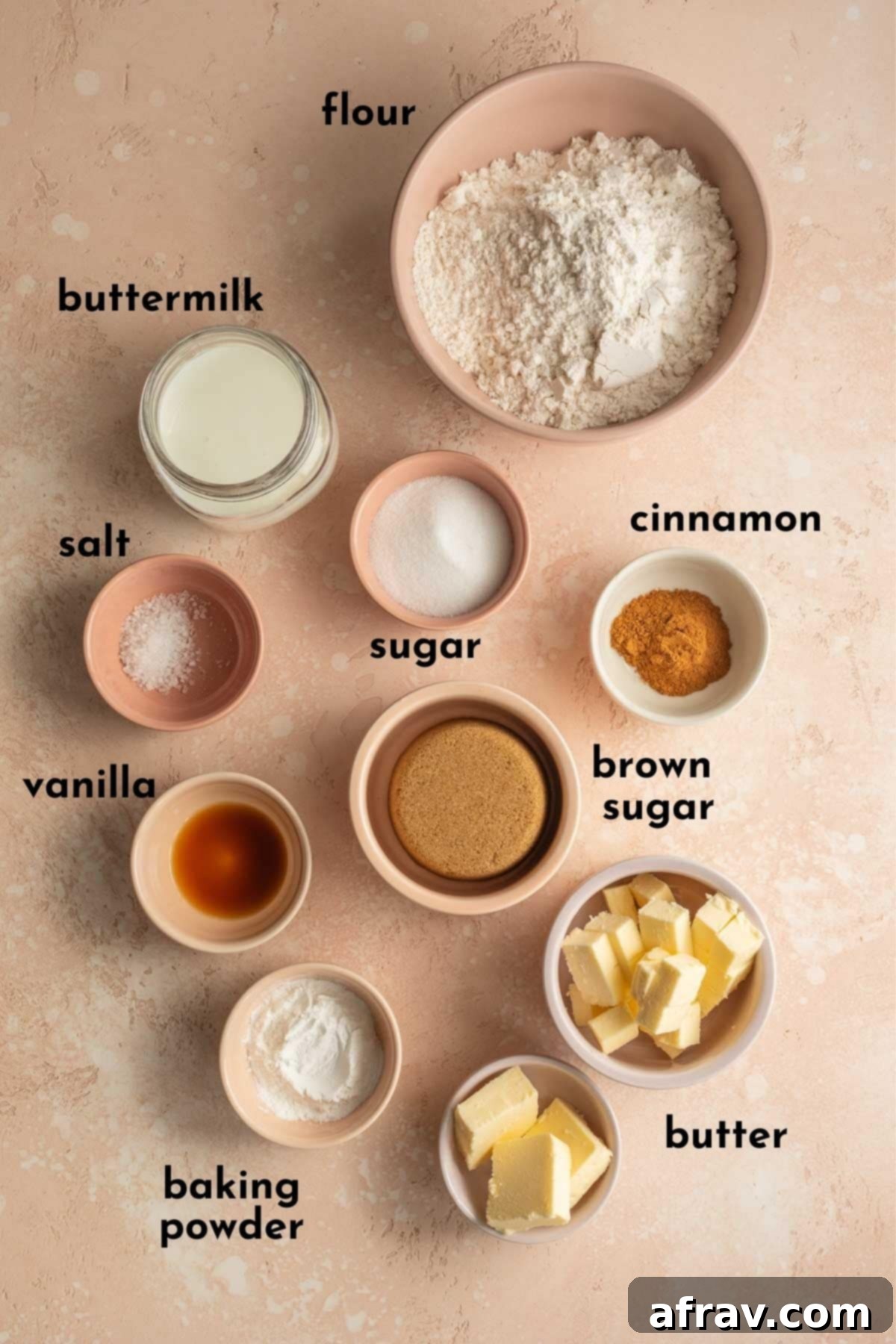 Arrangement of all ingredients needed for homemade air fryer cinnamon rolls, clearly labelled, on a white surface.