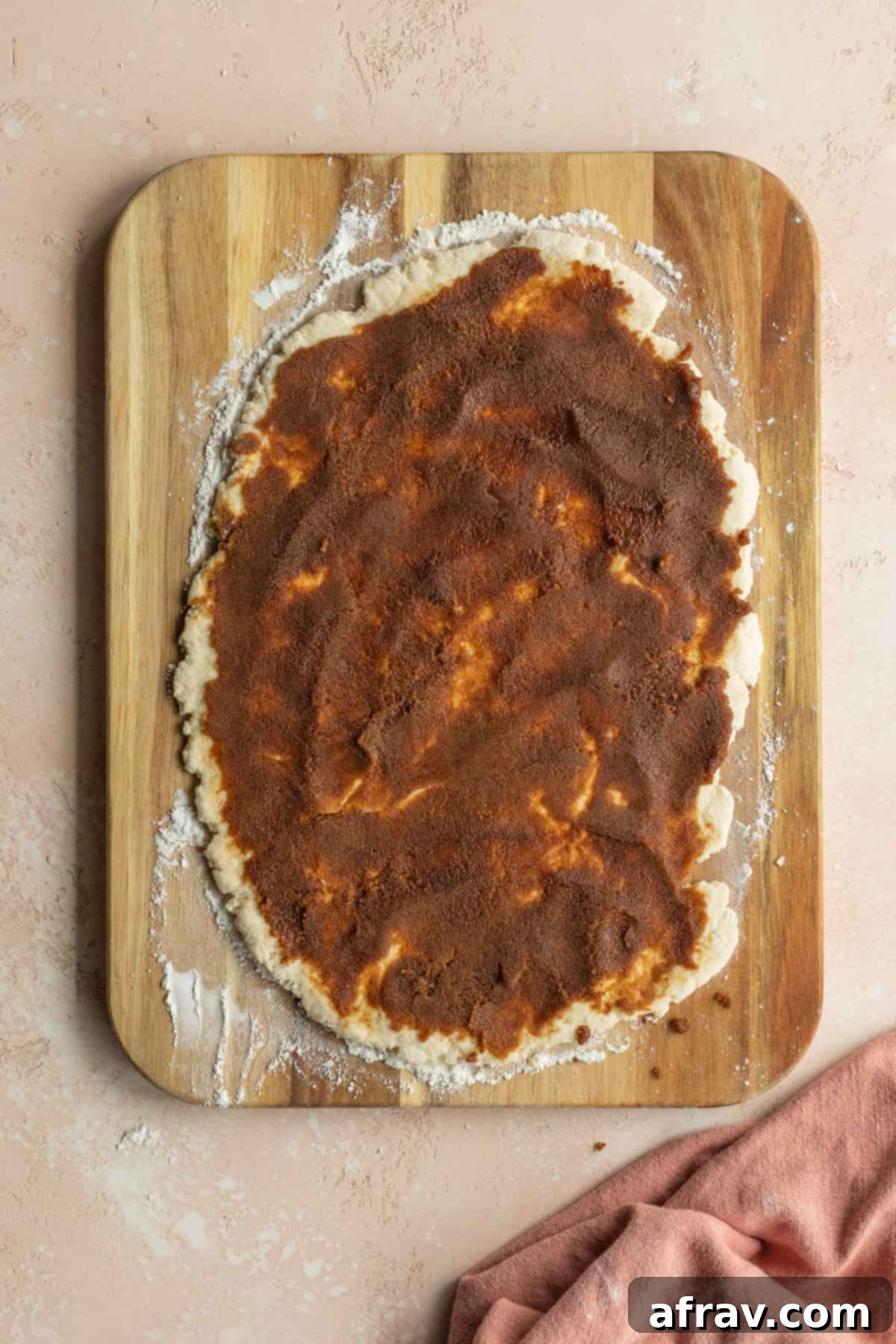 Cinnamon sugar filling evenly spread out on top of the rolled dough, ready to be rolled into a log.