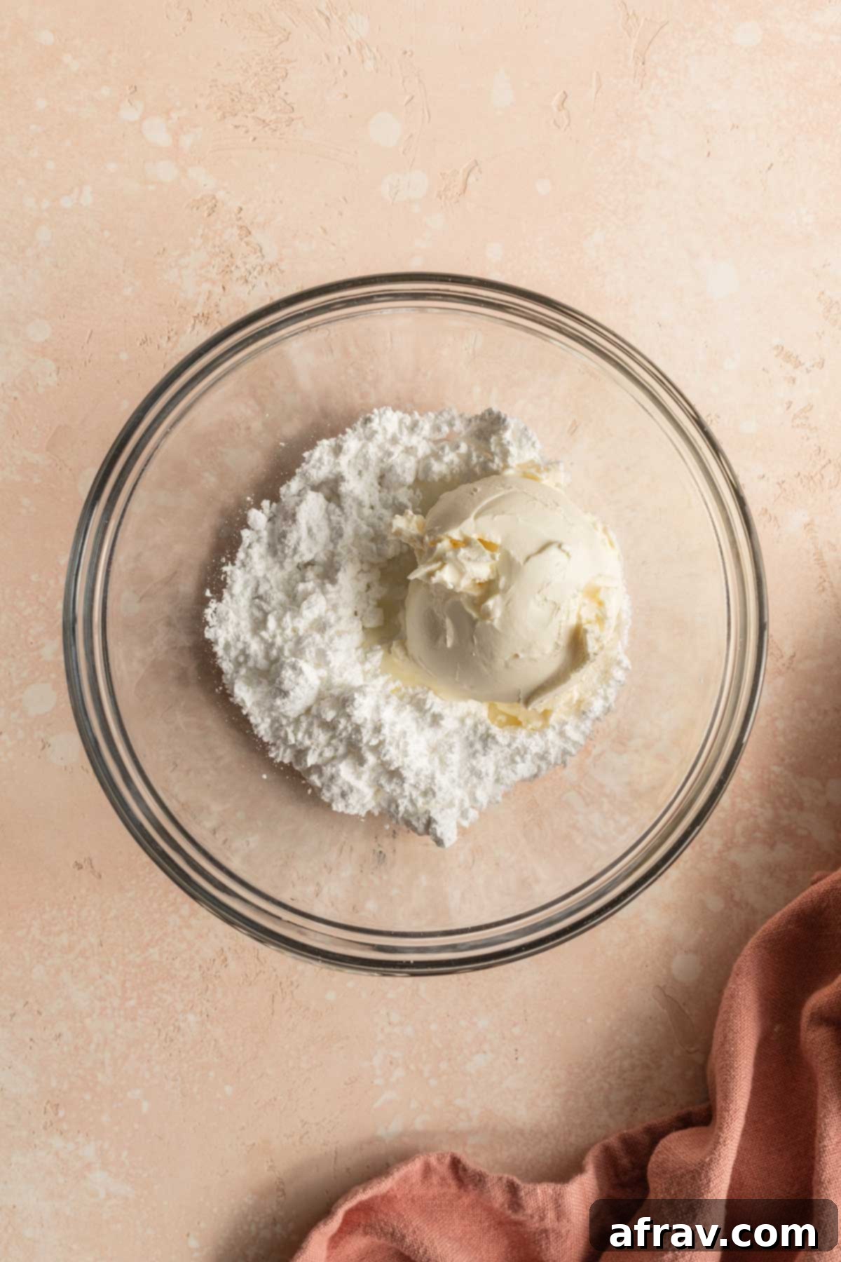 Ingredients for cream cheese frosting - powdered sugar and cream cheese - in a glass bowl.