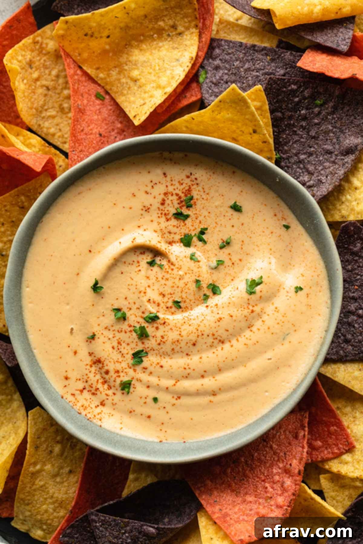 Overhead shot of a bowl of creamy chipotle sauce, perfectly drizzled, served with a side of crispy tortilla chips on a rustic wooden surface.