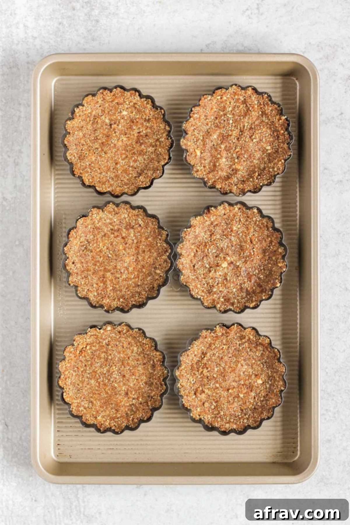 Effortless Fresh Vegan Fruit Tarts 6 Six mini tart pans, each filled with the pressed-in vegan crust mixture, ready for the next step.