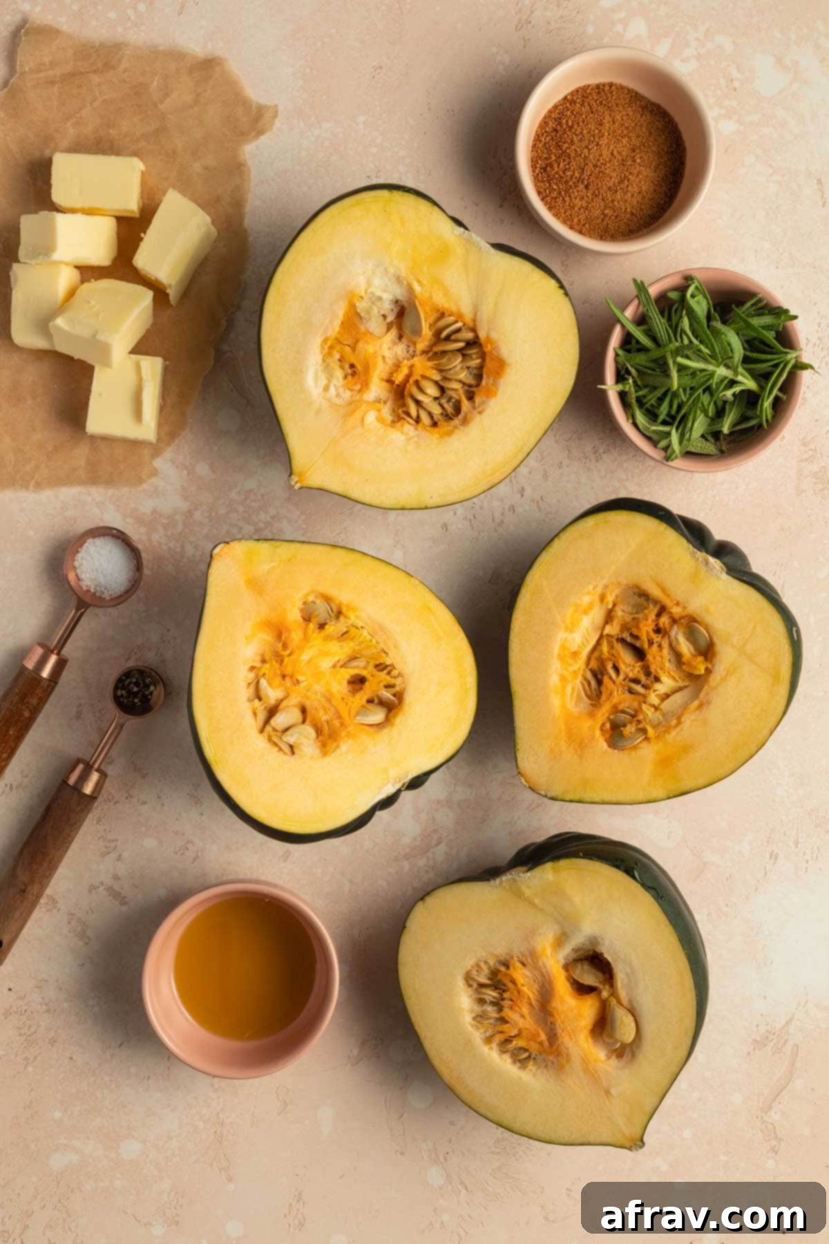 Overhead view of ingredients to make mashed acorn squash arranged individually: whole acorn squash, olive oil, salt, pepper, butter, rosemary, coconut sugar.