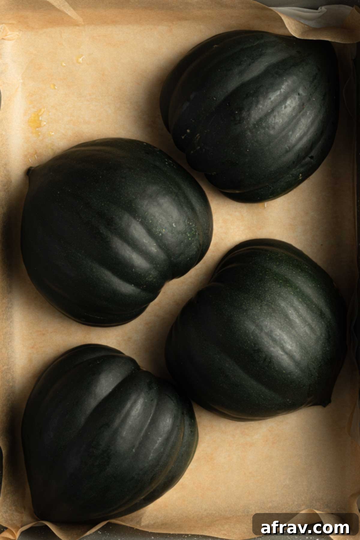 Acorn squash halves arranged cut side down in a roasting pan.