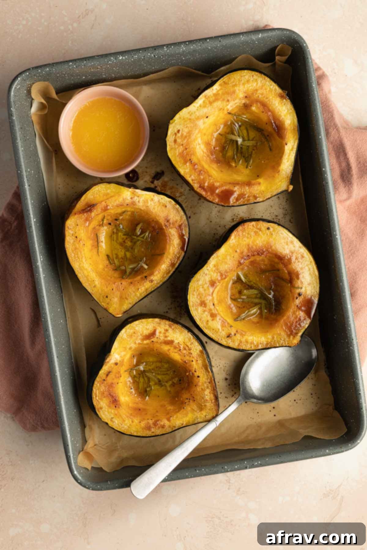 Roasted squash halves in a roasting pan after the first roast.
