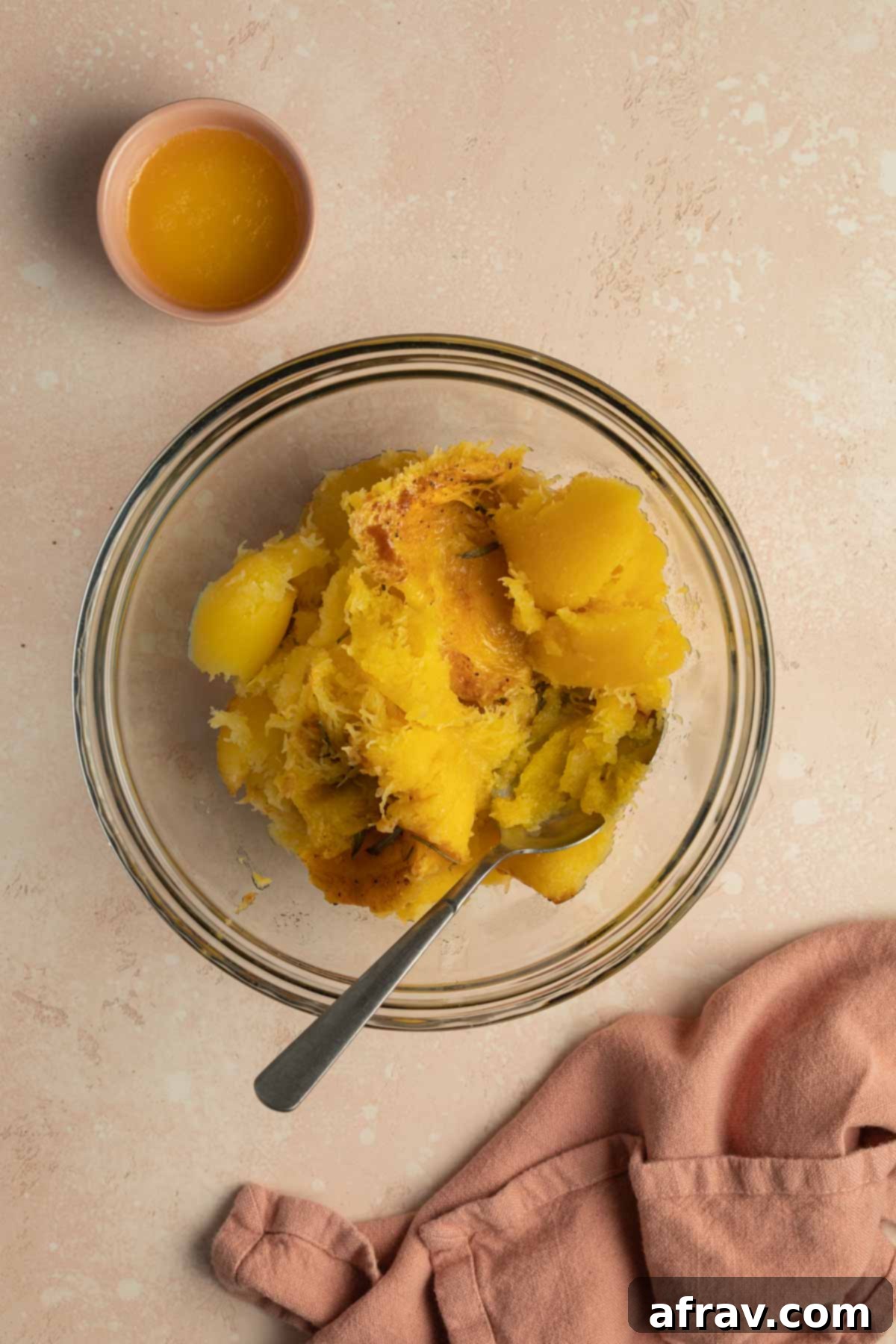 Roasted squash flesh scooped out into a glass bowl.