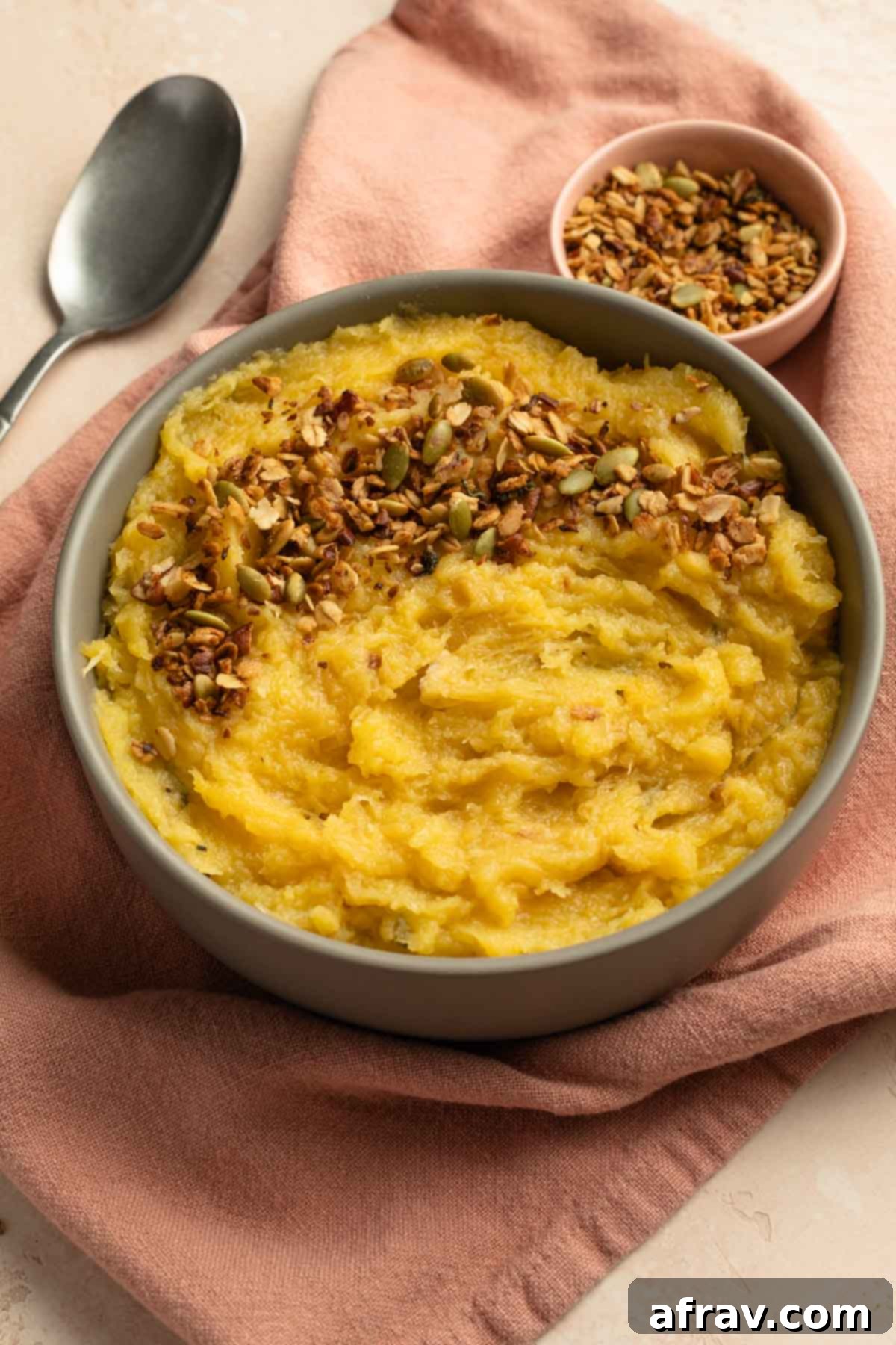 Side view of mashed squash topped with granola in a bowl.