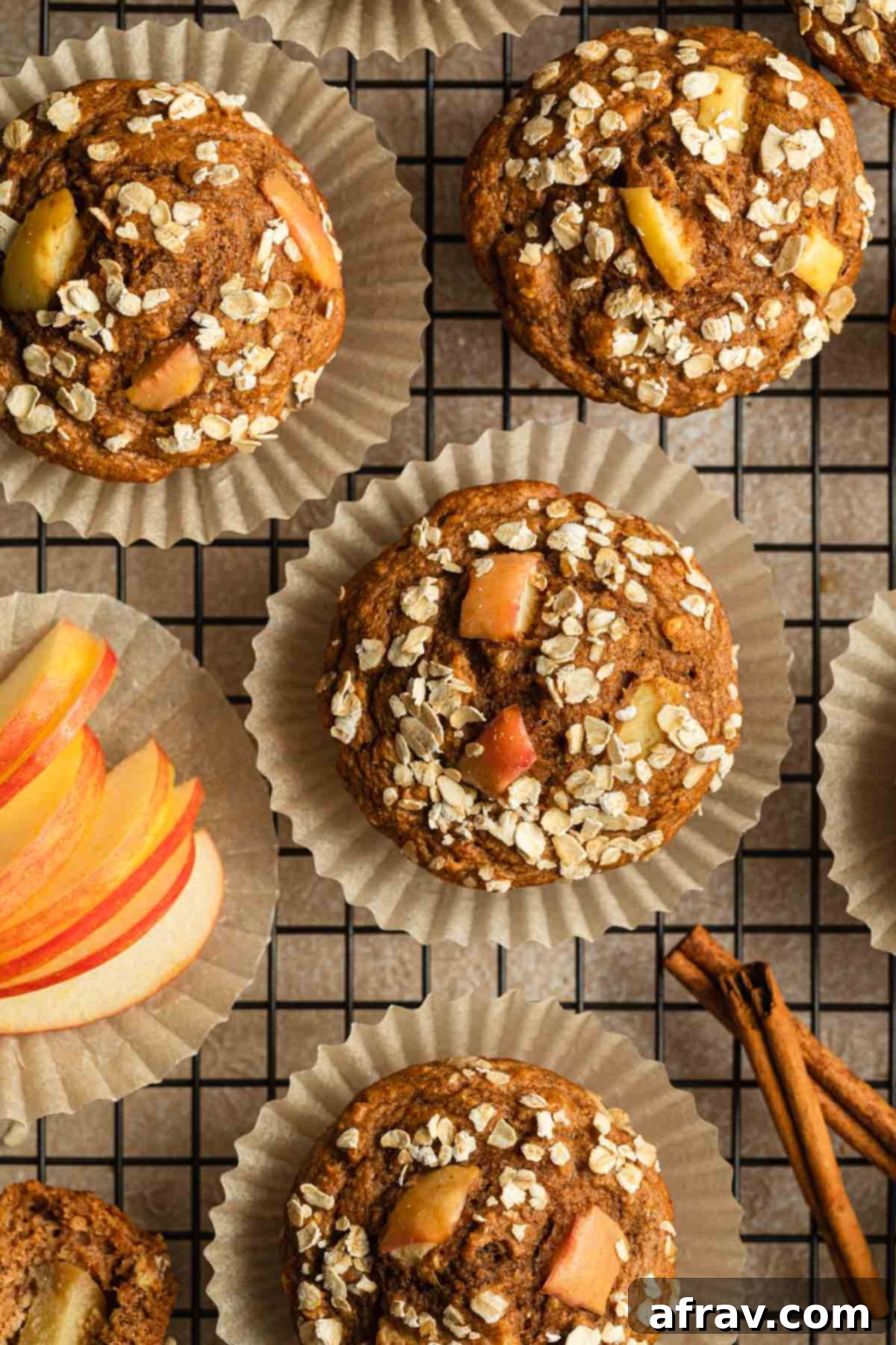 Overhead view of apple spice muffins arranged on a cooling rack, showcasing their golden-brown tops and apple pieces.