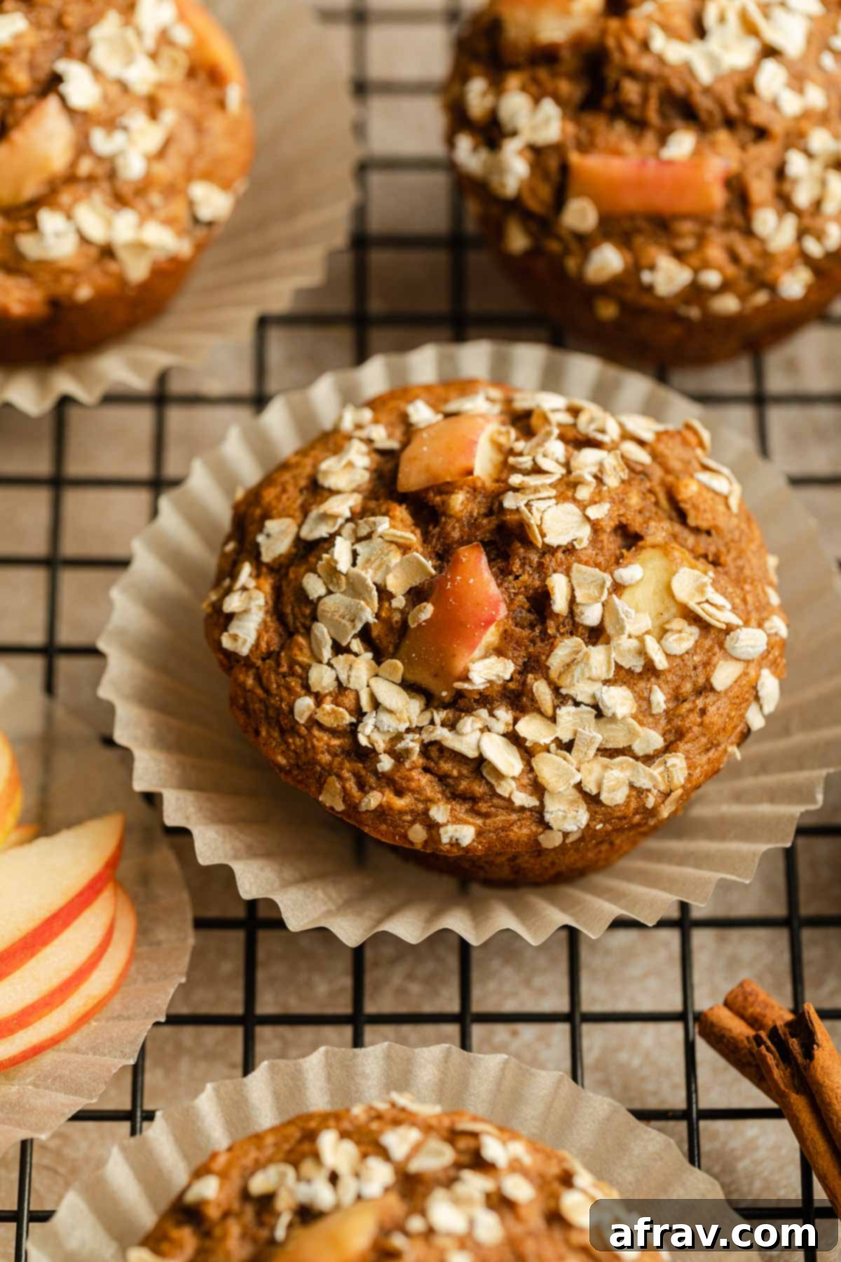 Close up view of a single apple muffin in a paper liner, placed on a wire rack.