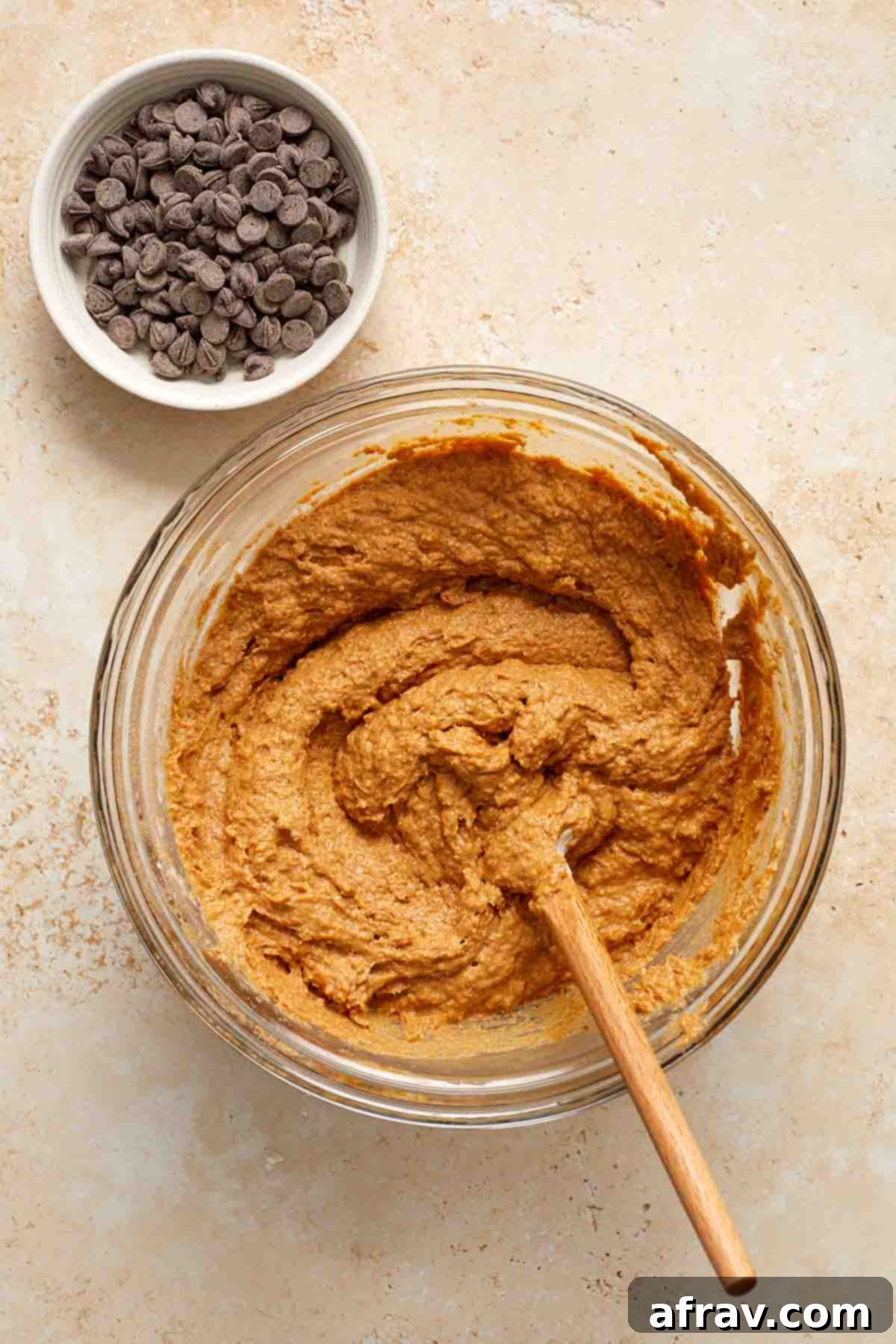 Batter stirred together in a glass bowl with chocolate chips on the side.