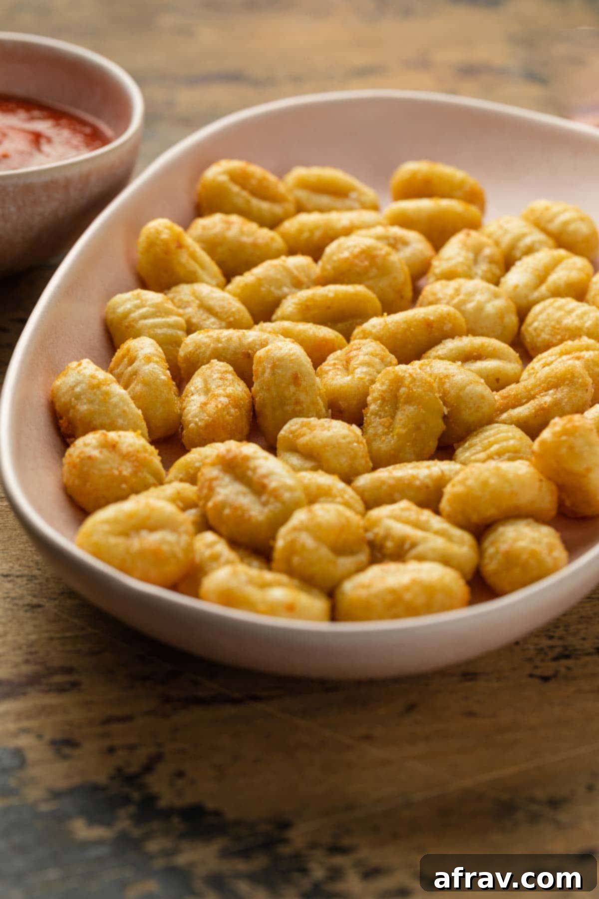 Crispy Air Fryer Gnocchi 6 Close up of perfectly air fried gnocchi served on a pink platter, showcasing its golden brown and crispy texture.
