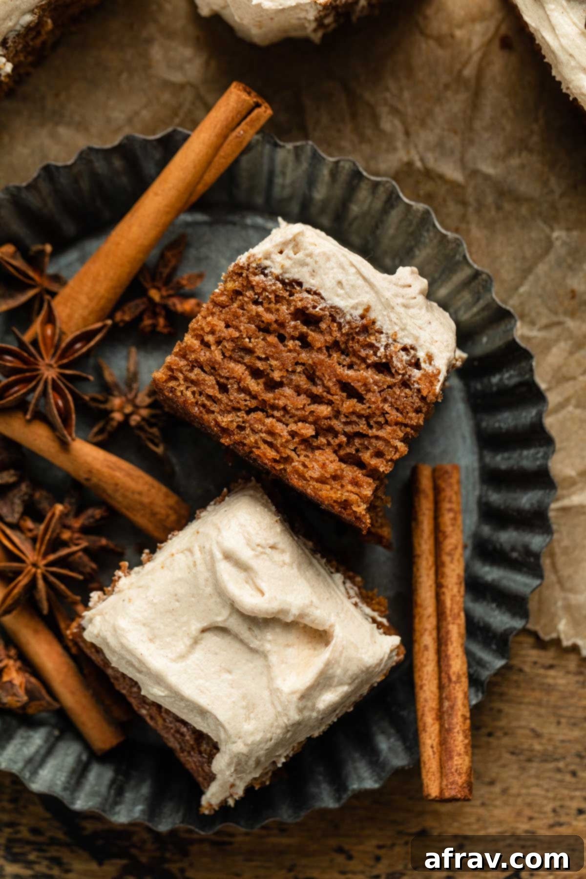 Two pieces of vegan apple spice cake arranged on a vintage pie plate with cinnamon sticks and star anise, showcasing its tender crumb and creamy frosting.