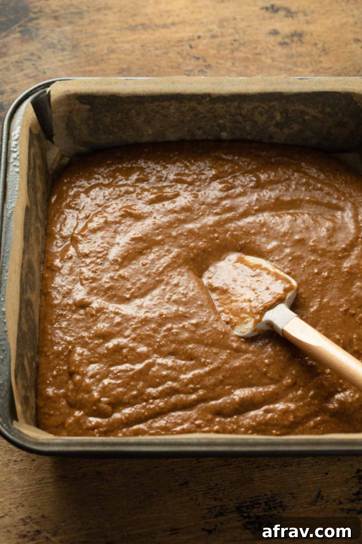 Smooth apple spice cake batter spread evenly in a square baking pan before baking.