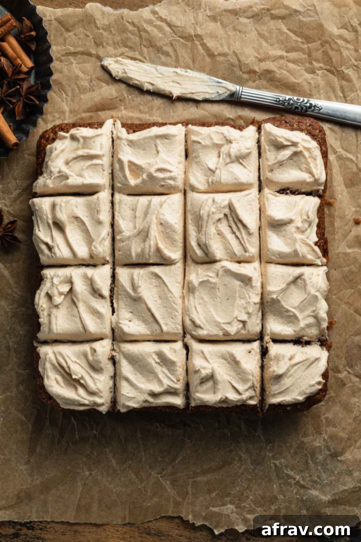 Overhead view of a perfectly frosted apple spice cake, pre-sliced into neat squares, ready for serving.