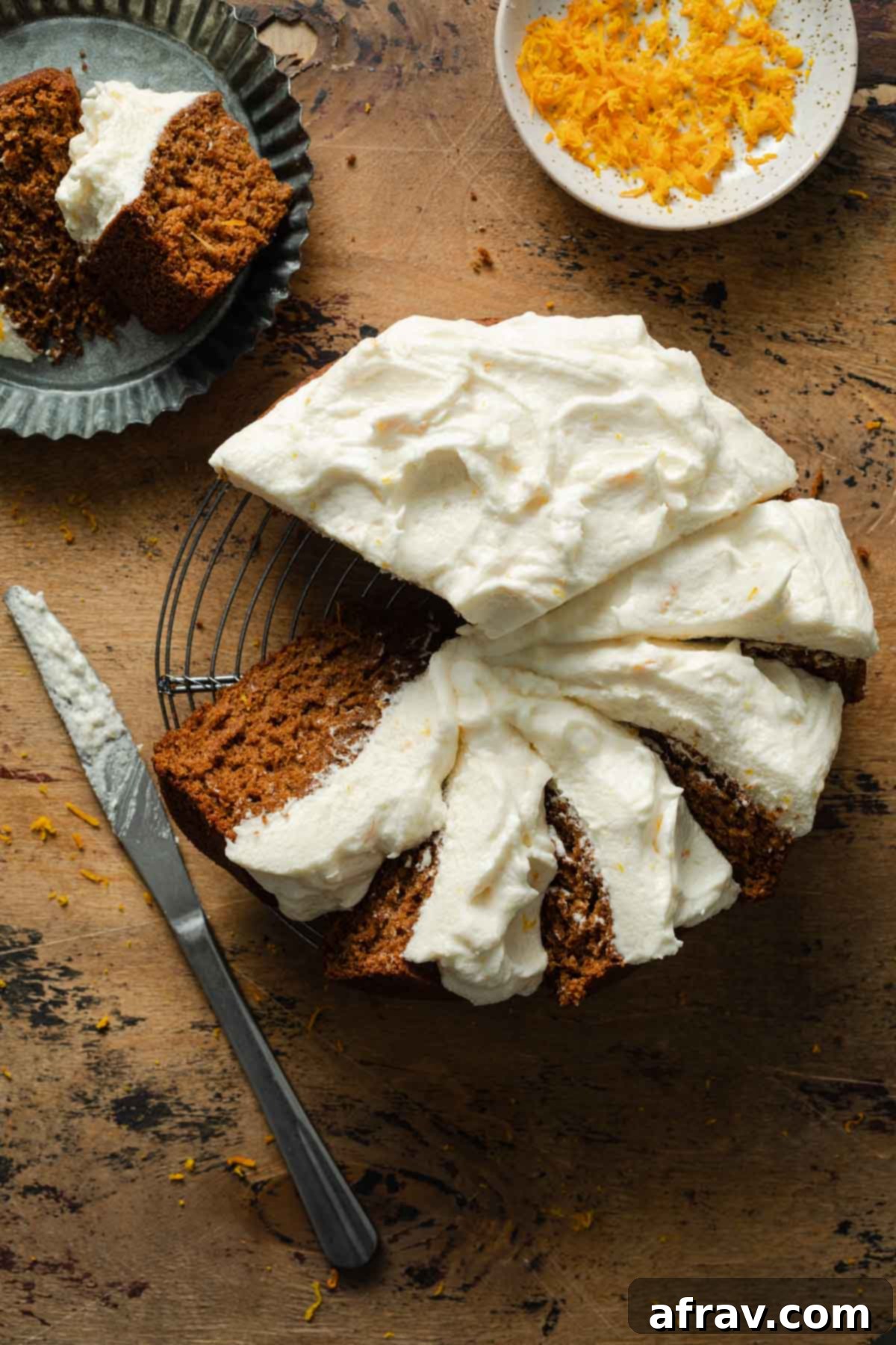 Orange spice cake topped with thick cream cheese frosting, artfully sliced and arranged on a wire rack, ready to serve.