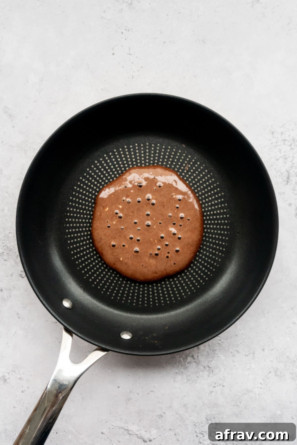 Chocolate pancake batter on a frying pan.