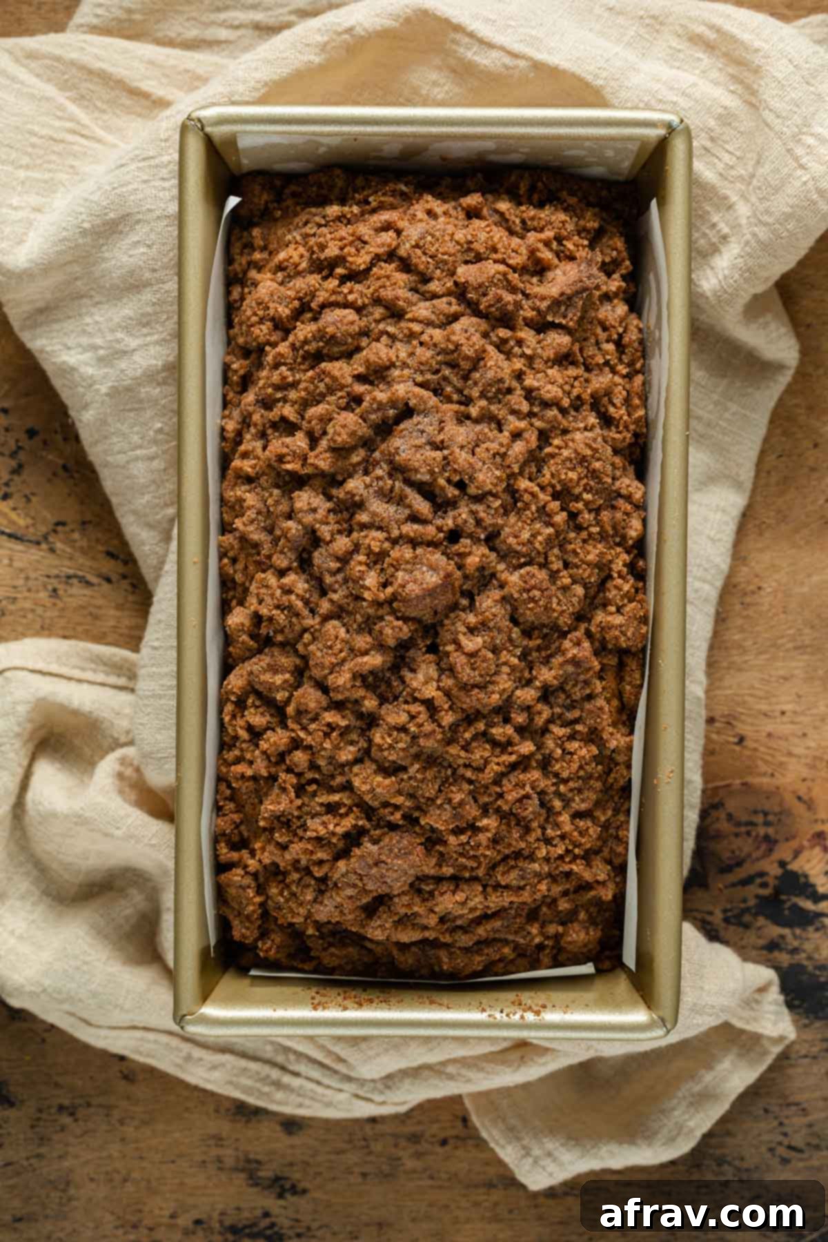 Overhead view of a baked butternut squash bread with a golden crumb topping, still in its loaf pan.