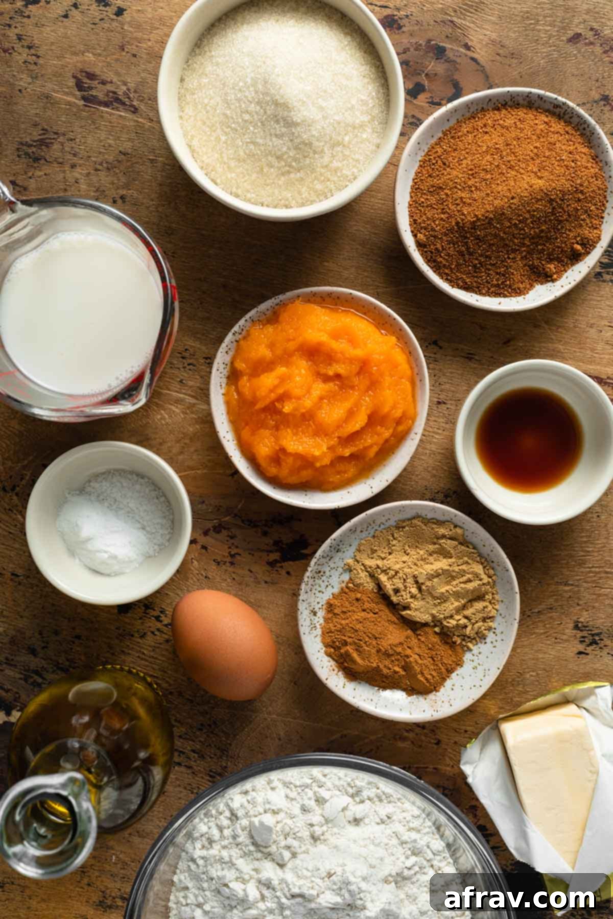 Ingredients to make butternut squash bread arranged in individual bowls, including spices, flour, sugar, and squash puree.