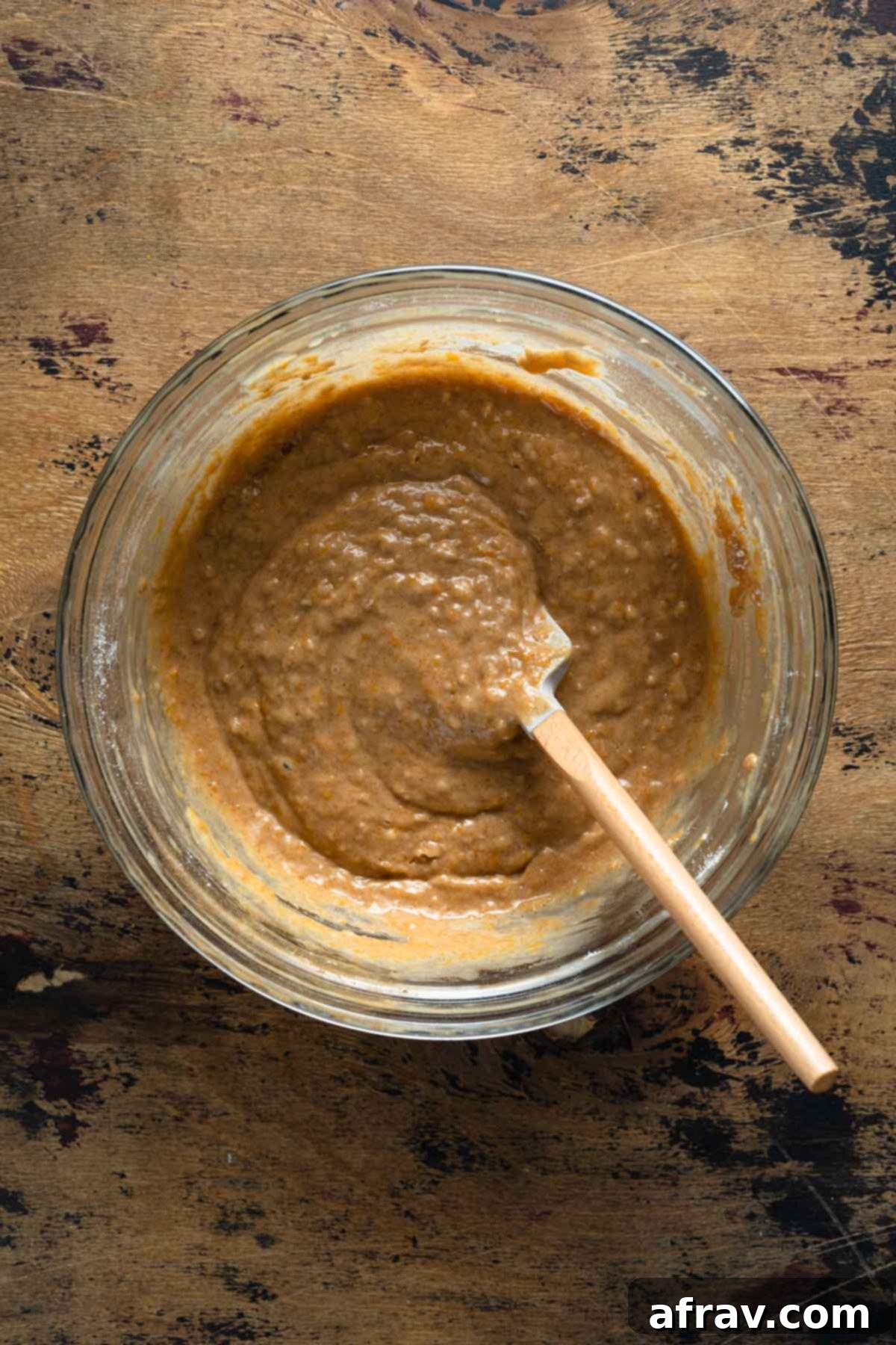 Bread batter being stirred in a glass bowl with a spatula, highlighting the smooth texture.