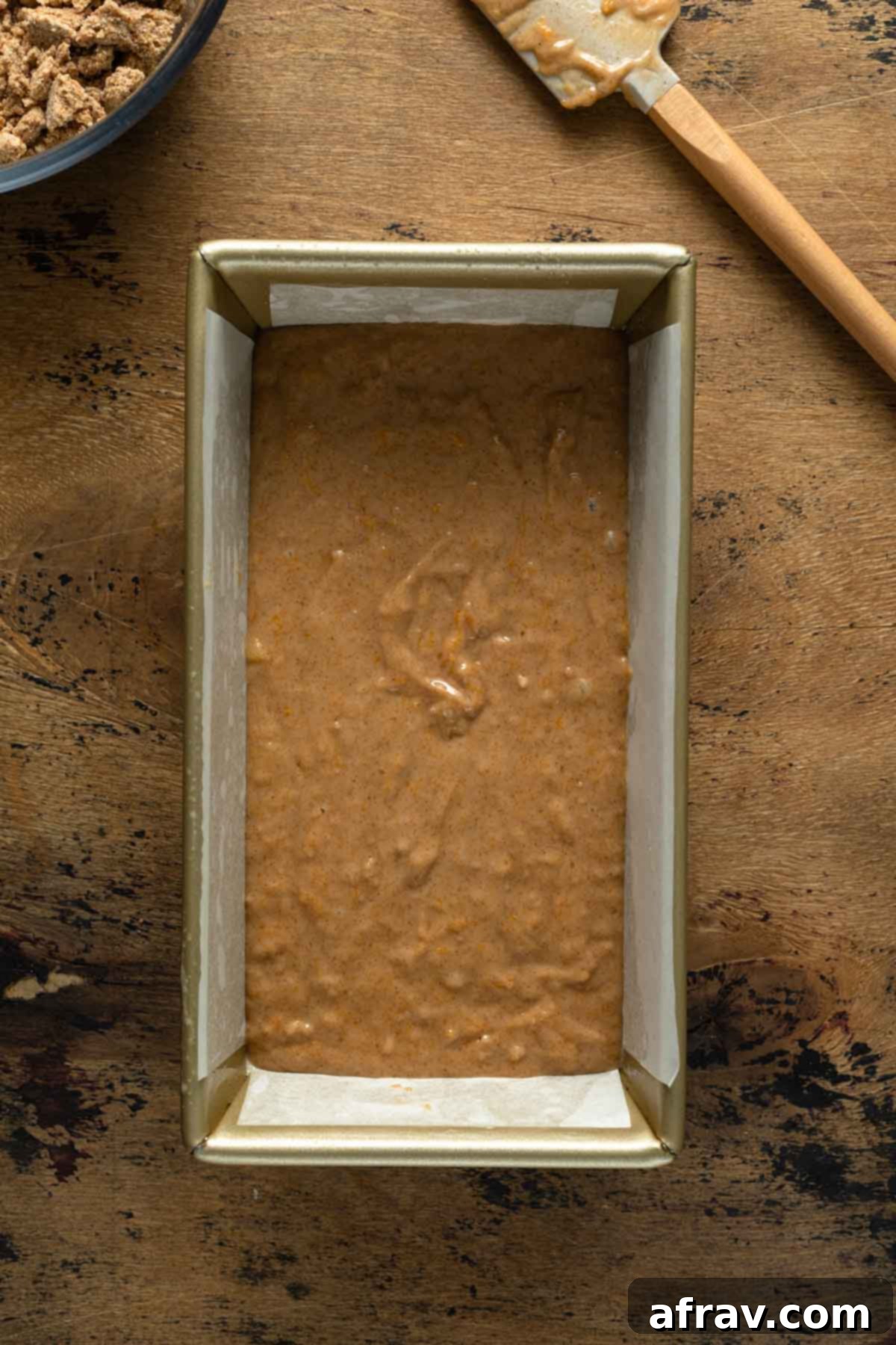 Overhead view of bread batter poured into a parchment-lined loaf pan, ready for topping.