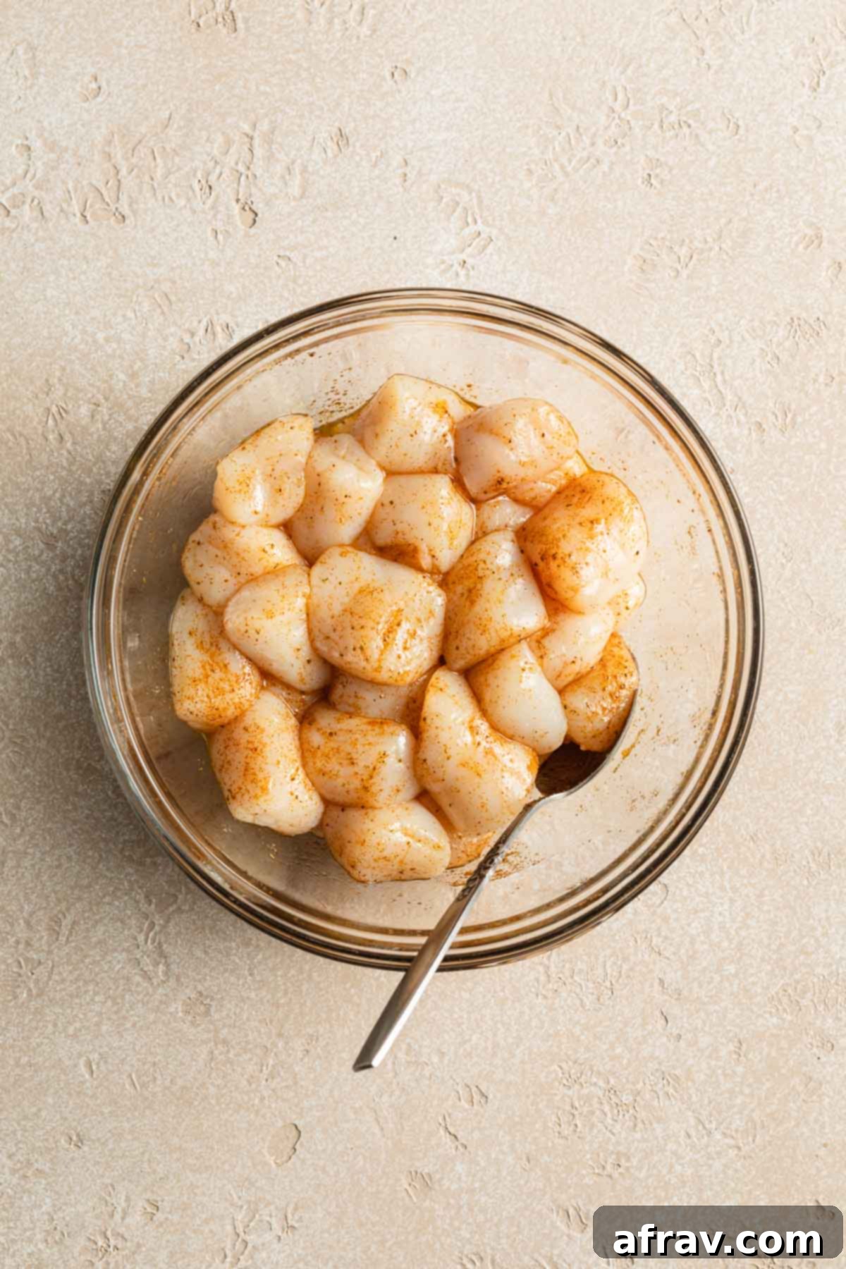 Air Fryer Scallops 4 Raw scallops in a glass bowl and tossed with seasoning.