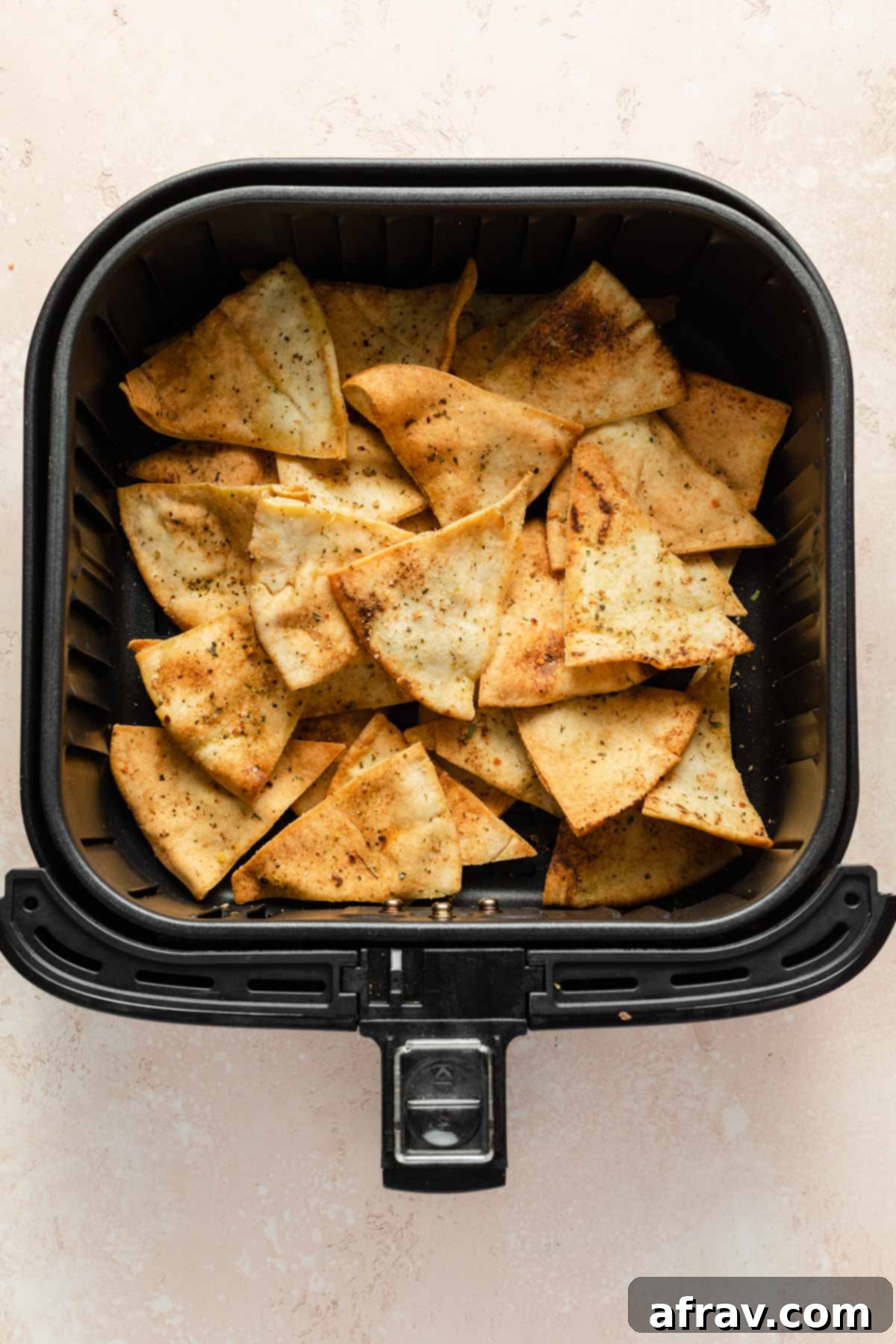Pita chips in an air fryer basket.