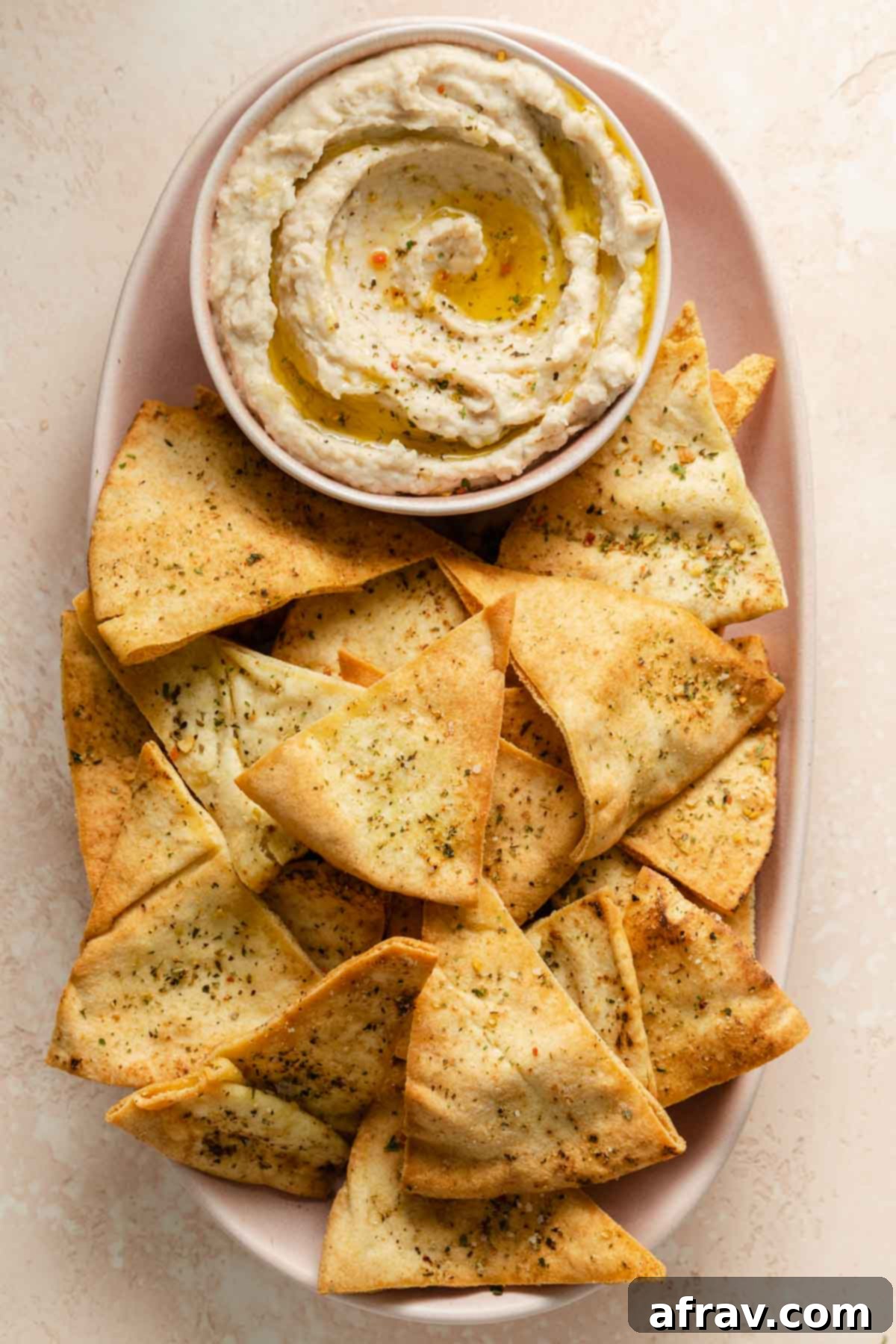 Overhead view of air fried pita chips on a platter with white bean dip.