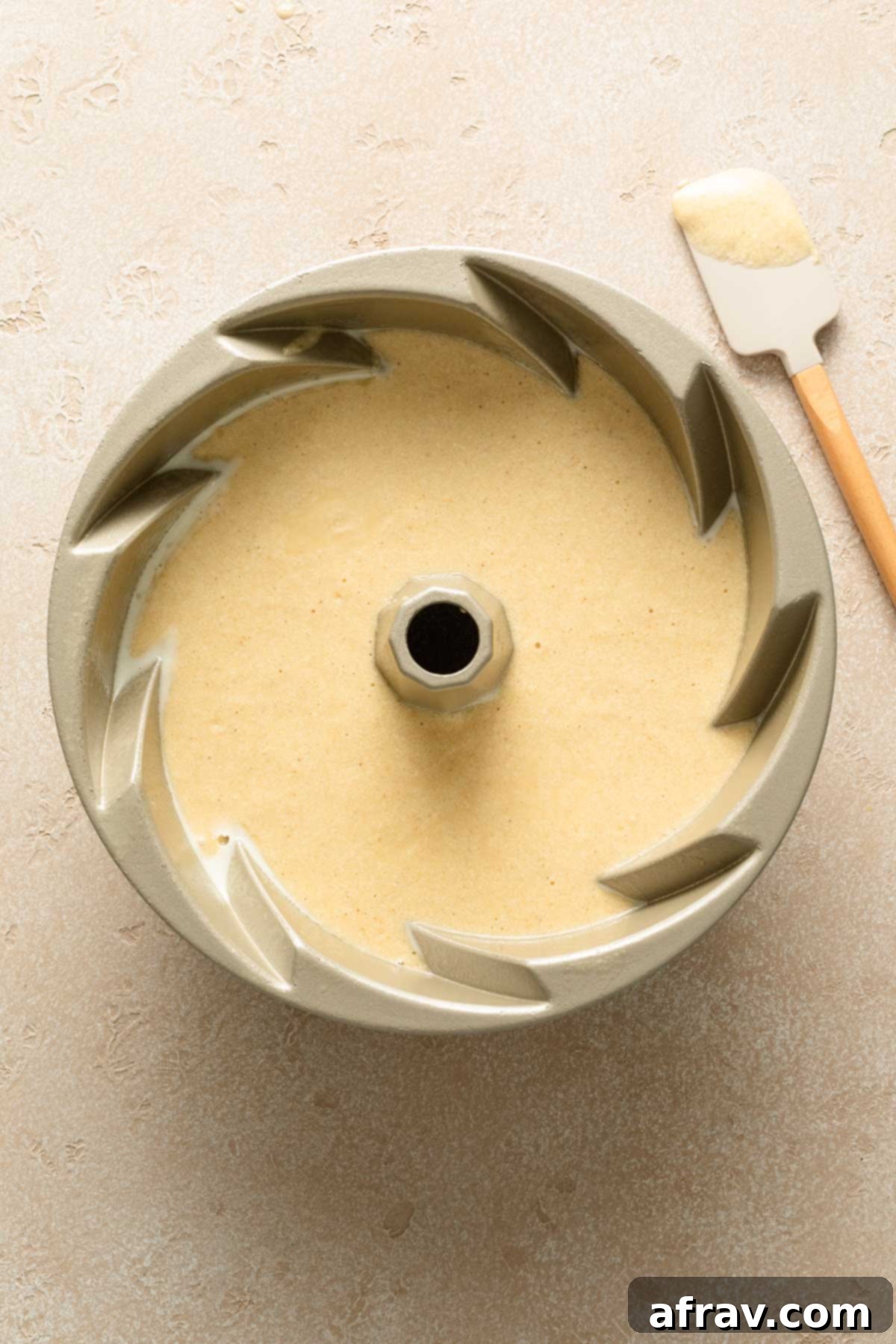 Eggnog cake batter evenly distributed in a greased bundt pan, showing its smooth texture before baking.