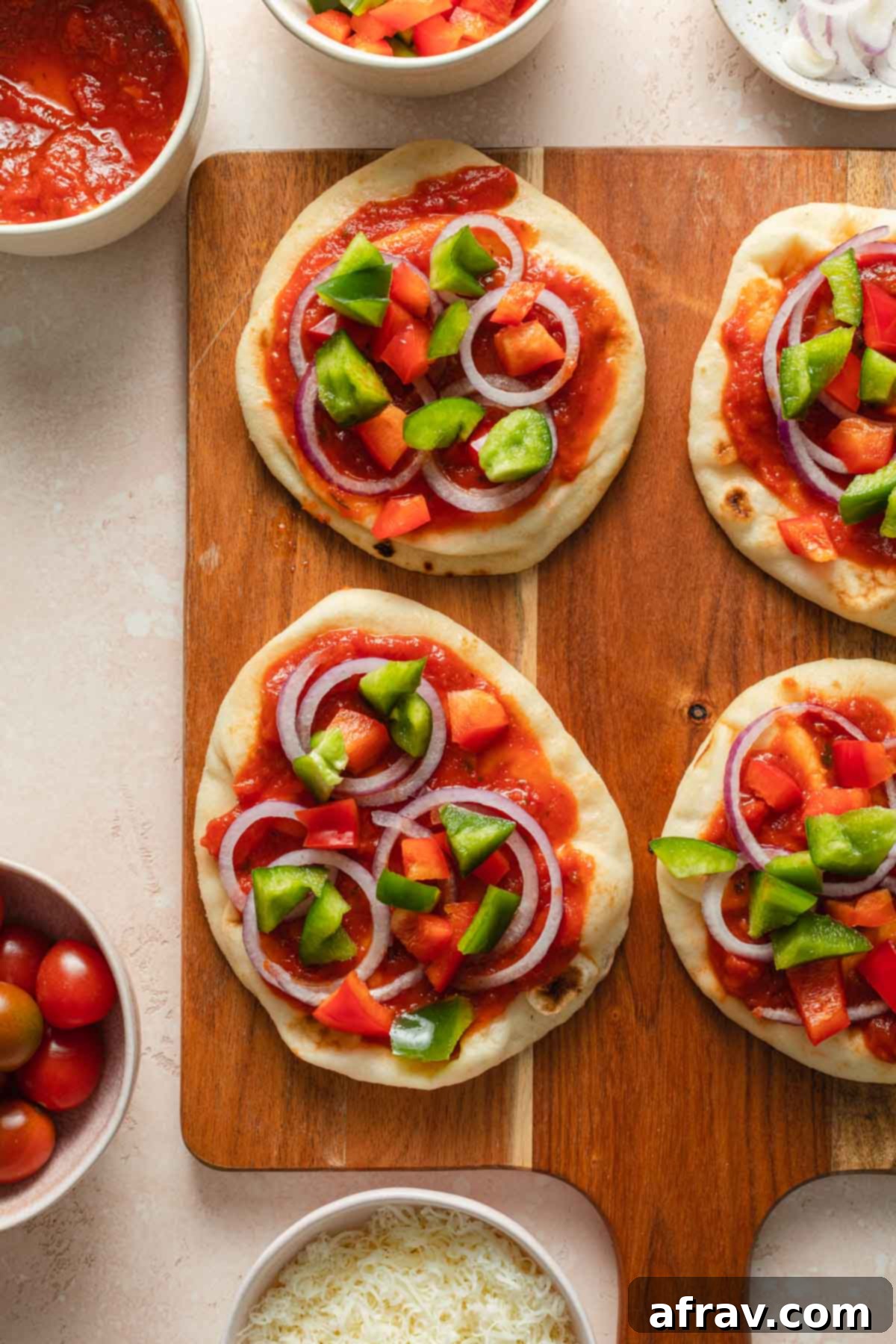 Naan bread mini pizzas with veggies arranged on top.