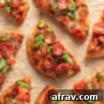 Overhead view of naan bread air fryer mini pizzas cut into pieces and arranged on parchment paper.
