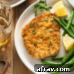 Crispy Air Fryer Pork Schnitzel 10 Air fryer pork schnitzel on a white plate with green beans and a lemon wedge.
