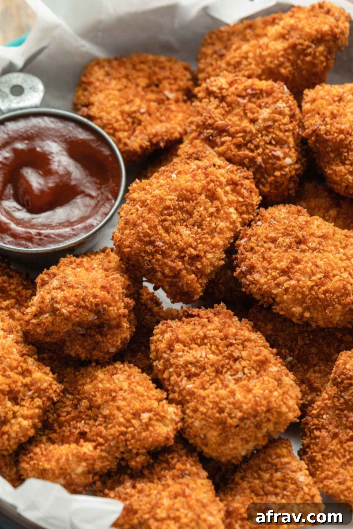 Crispy breaded chicken nuggets arranged on a platter with barbecue dipping sauce on the side.