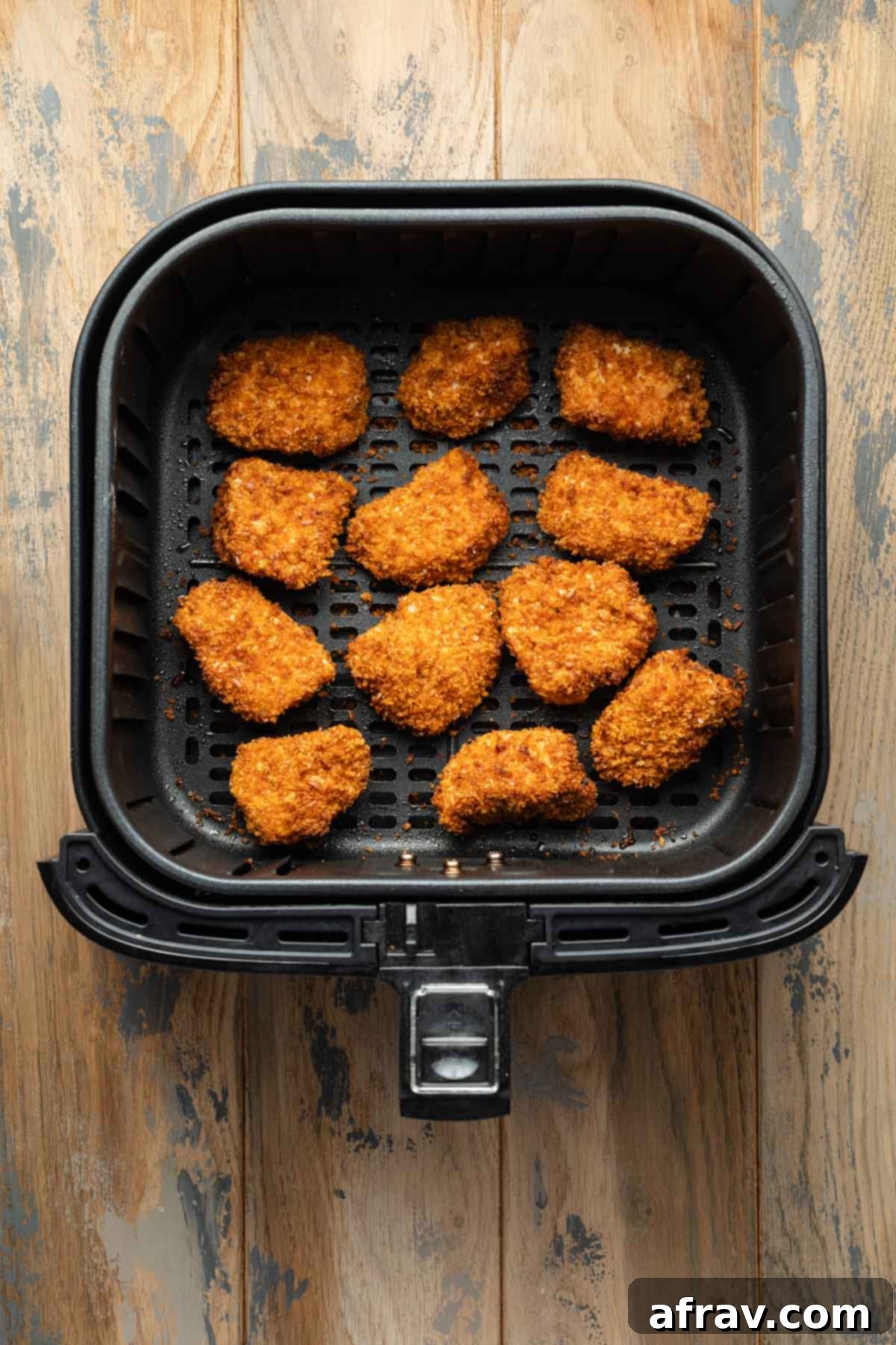 Perfectly air-fried golden-brown chicken nuggets, crispy and cooked, resting in an air fryer basket.