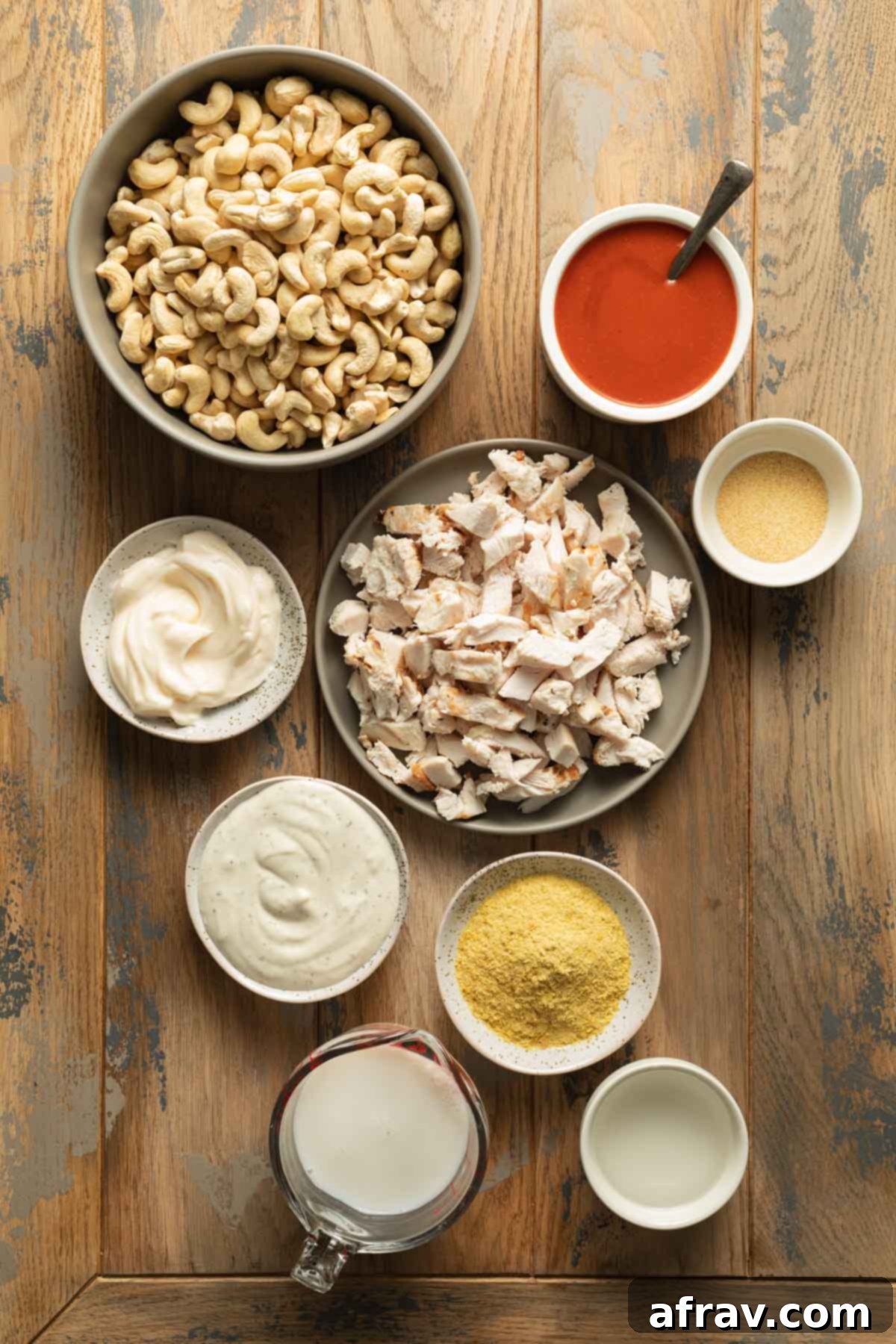 Creamy Dairy-Free Buffalo Chicken Dip 3 Ingredients to make buffalo chicken dip arranged individually on a wooden surface.
