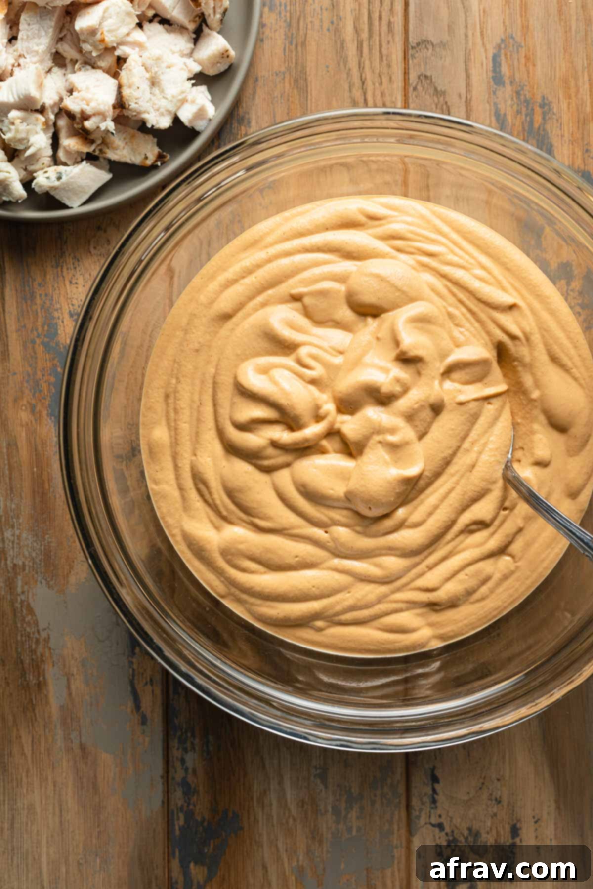 Creamy Dairy-Free Buffalo Chicken Dip 5 Creamy cashew mixture in a glass bowl next to a plate of chopped chicken.