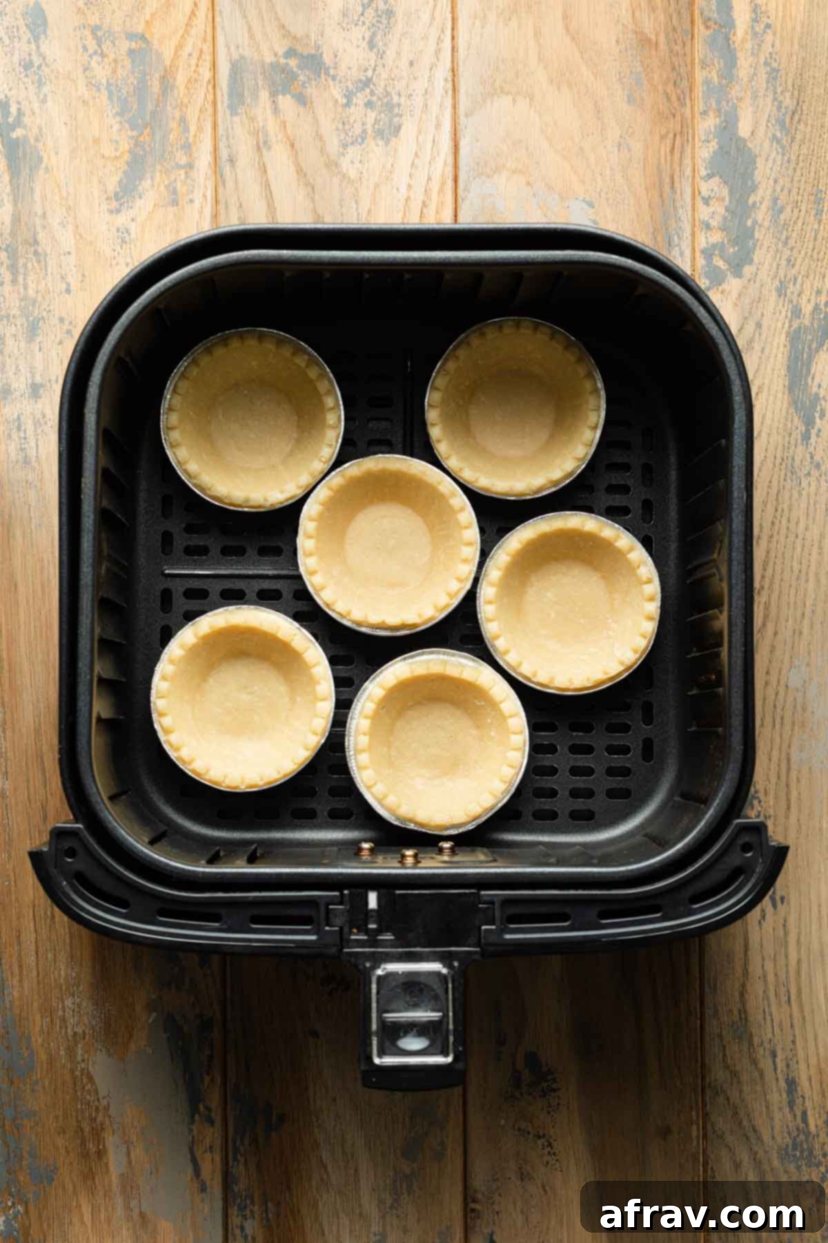Unbaked tart shells in an air fryer basket.