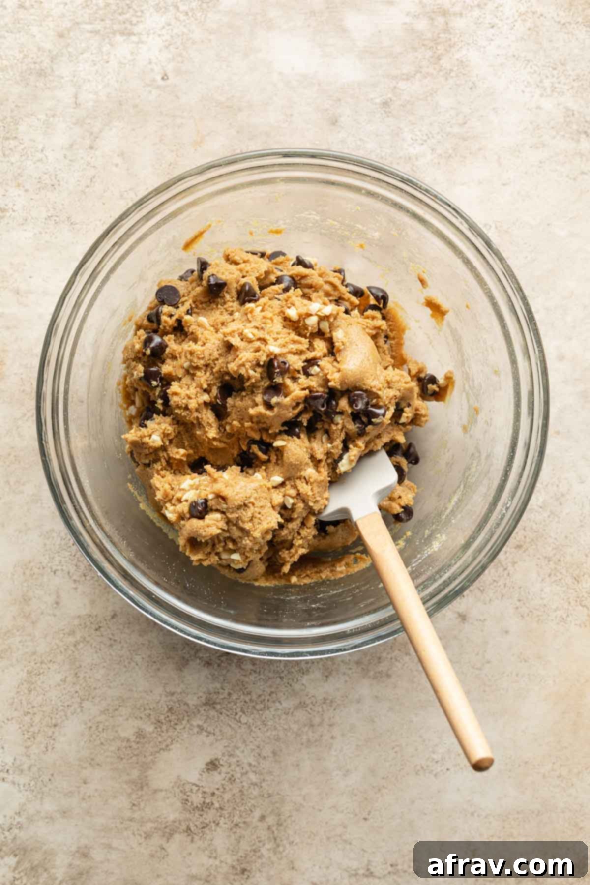Cookie dough mixed with chocolate chips and peanuts in a glass bowl, demonstrating the generous amount of mix-ins.