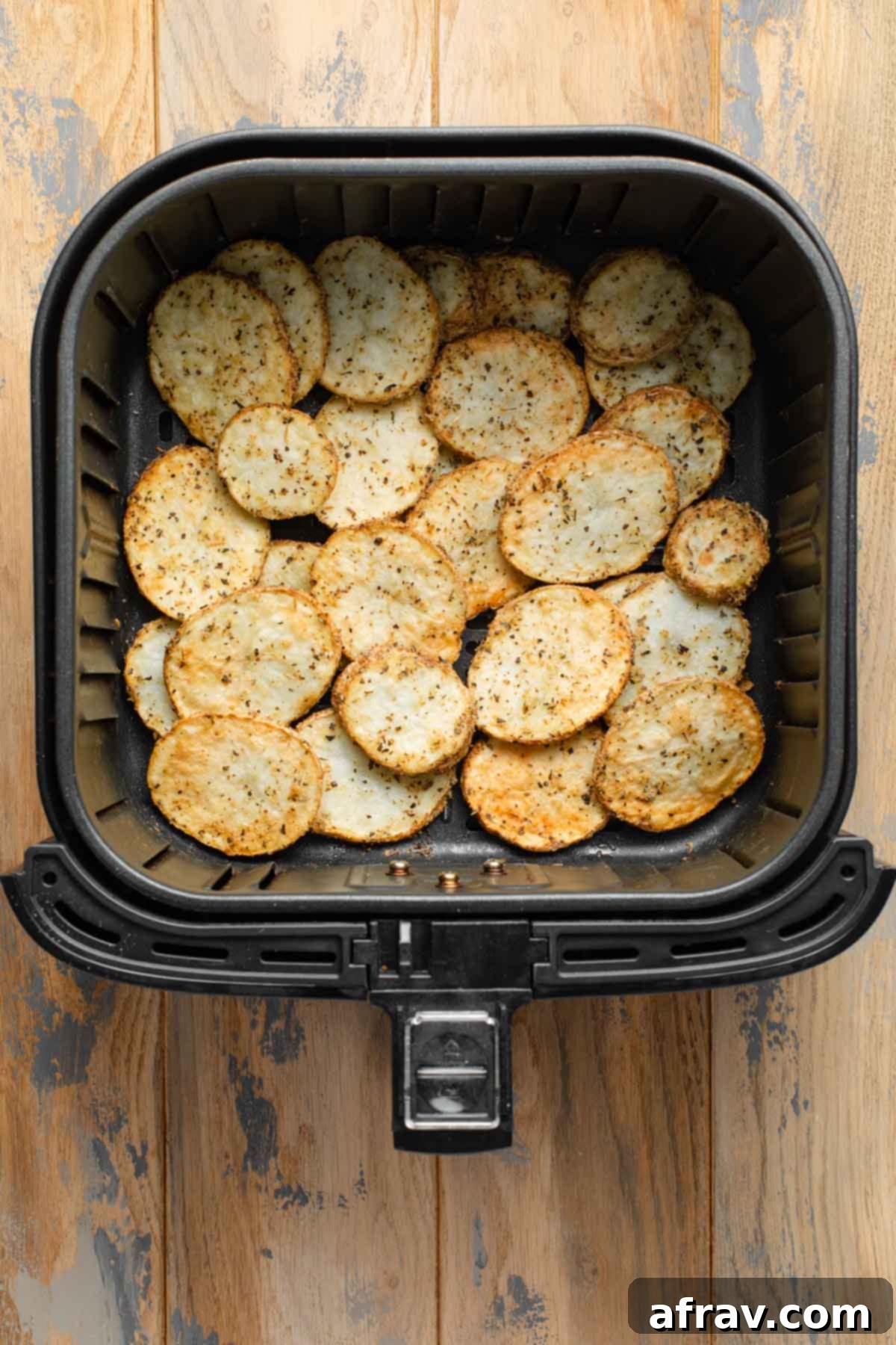 Air fried sliced potatoes in an air fryer basket.