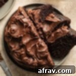 Overhead view of air fryer cake topped with chocolate frosting and cut into some slices.