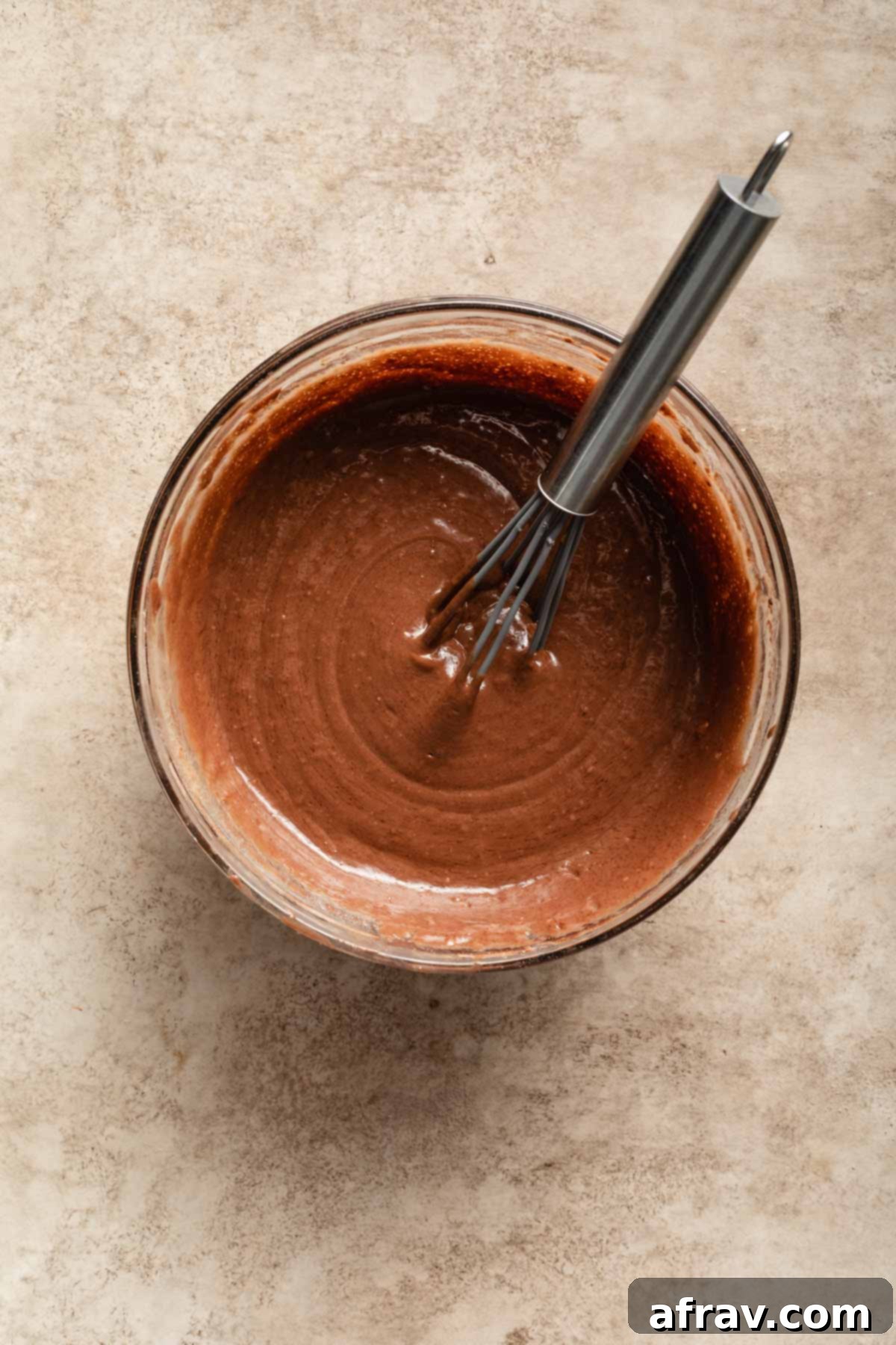 Cake batter in a glass bowl with a whisk.