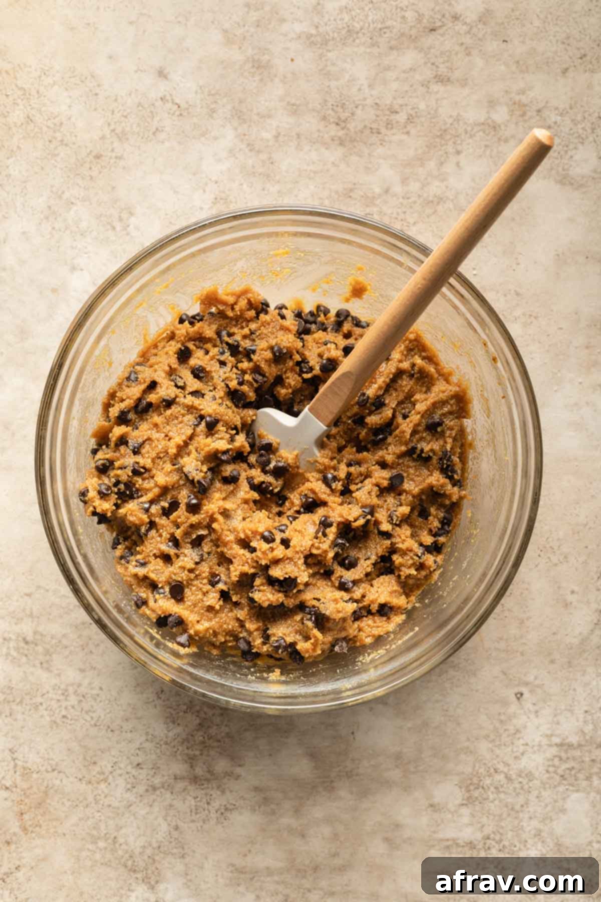 Cookie dough in a glass bowl with a spatula.