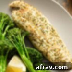 Close up view of a piece of air fryer tilapia on a plate with roasted broccoli.