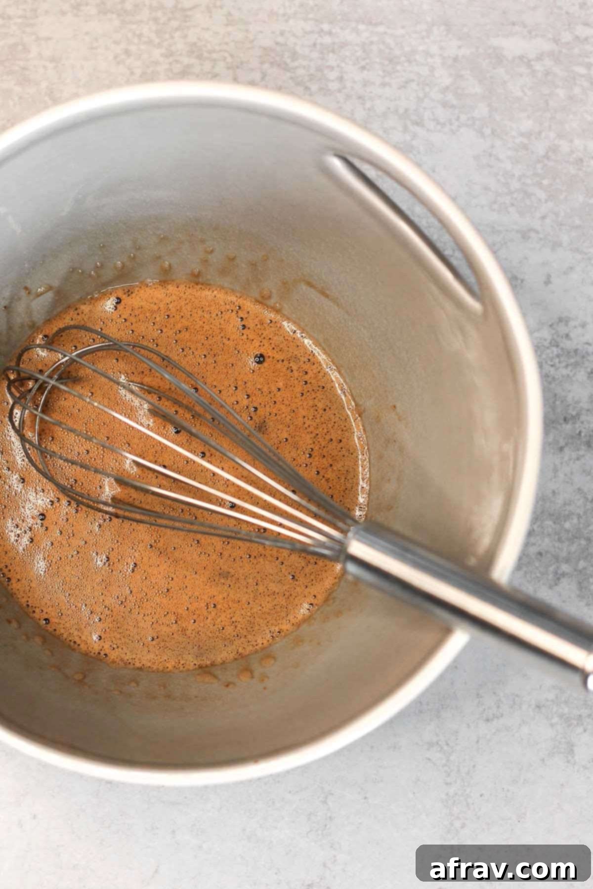 Wet ingredients with a whisk in a gray mixing bowl.
