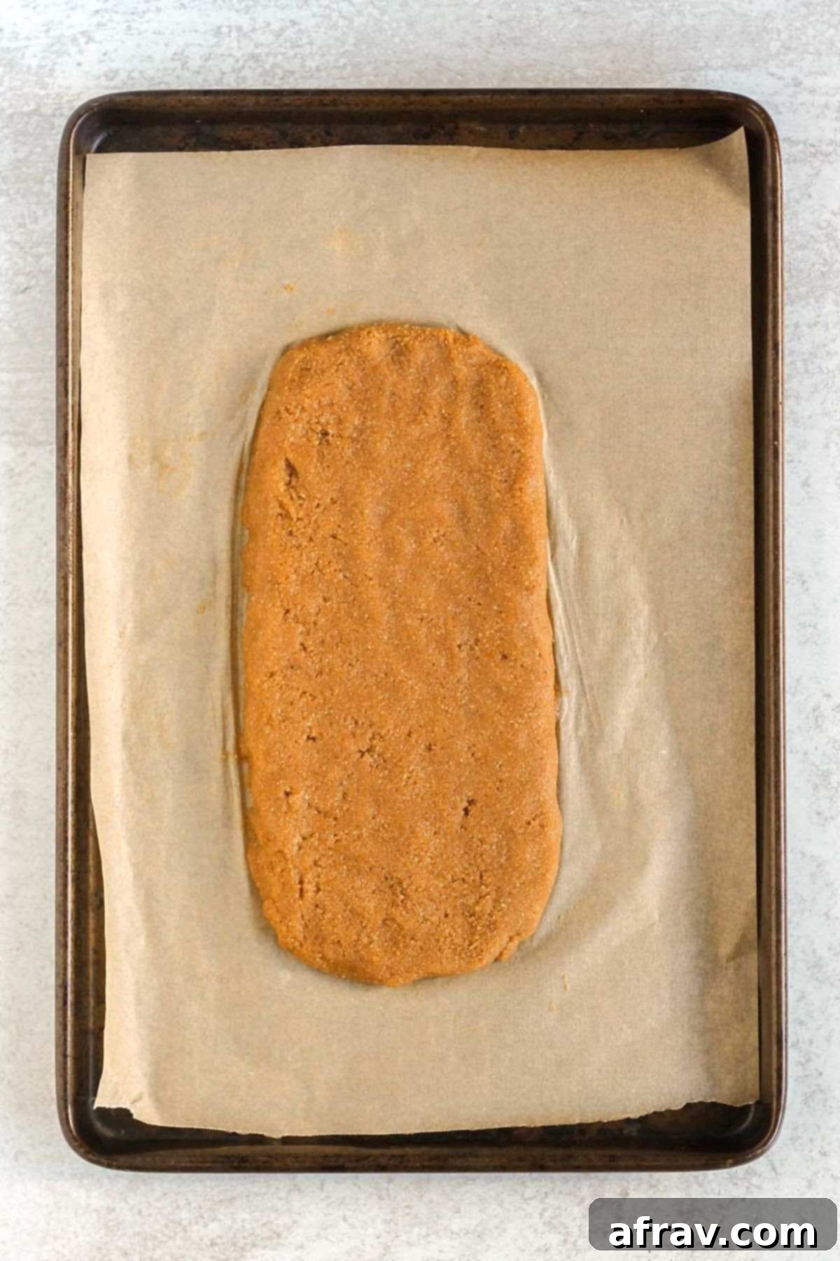 Almond flour biscotti dough shape into a log on a parchment paper lined baking sheet.