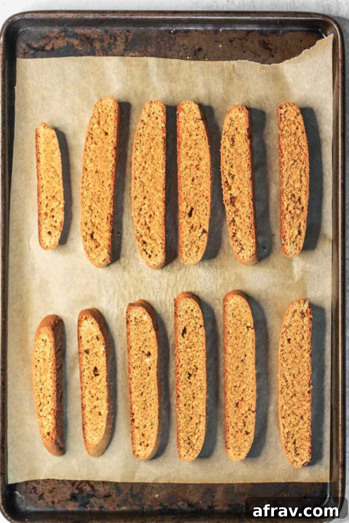 Sliced biscotti on a parchment paper lined baking sheet after baking the first time.