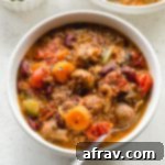 Slow cooker vegetarian chili with quinoa in a white bowl with a spoon.