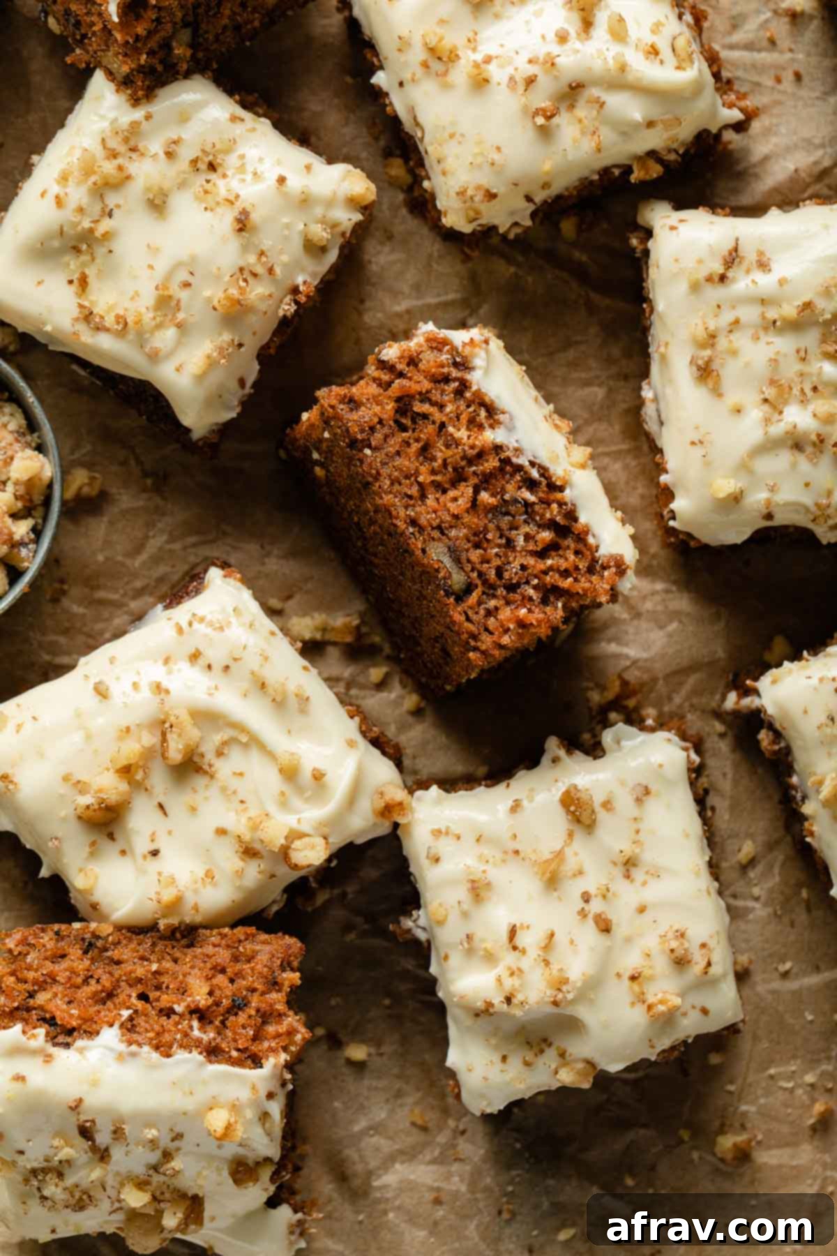 A beautifully cut small carrot cake, presented in squares on a sheet of parchment paper, ready to be enjoyed.