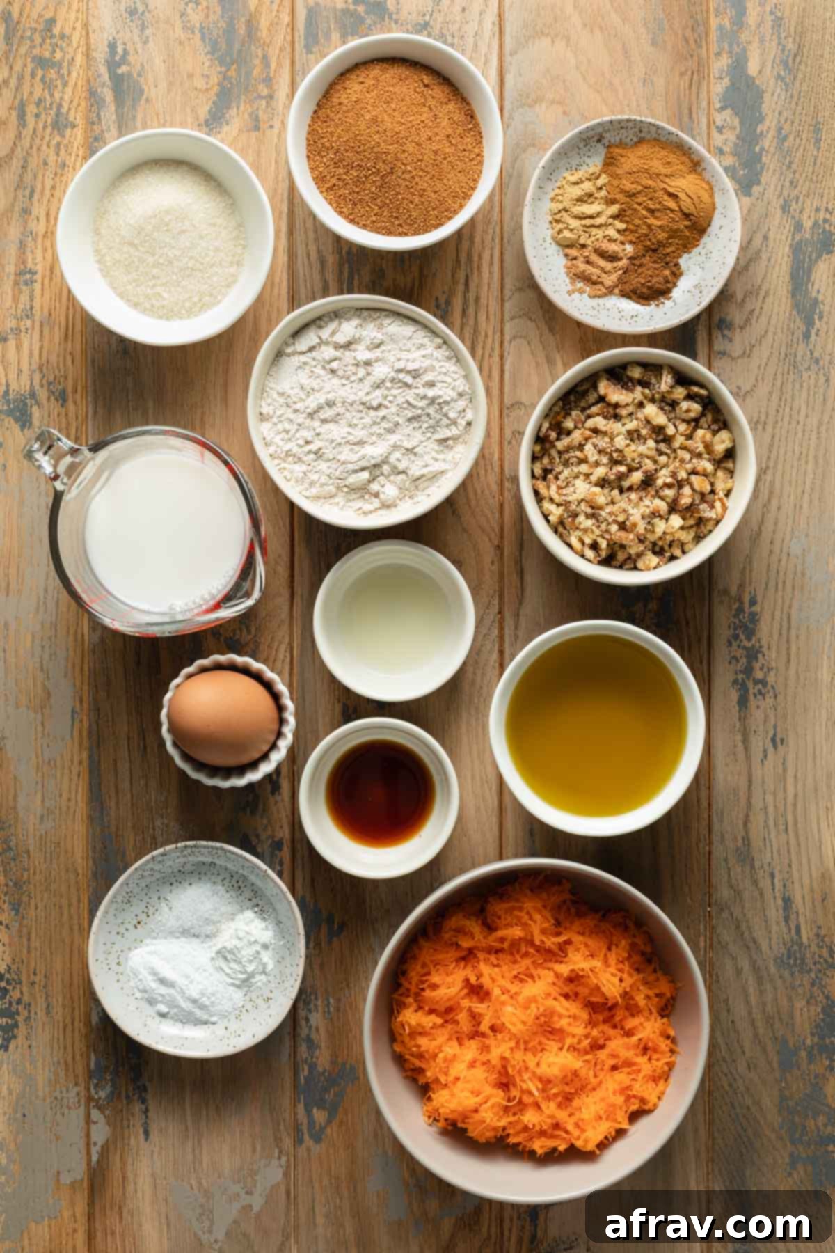 Carefully arranged ingredients for the small carrot cake recipe on a rustic wooden table surface, highlighting freshness and quality.
