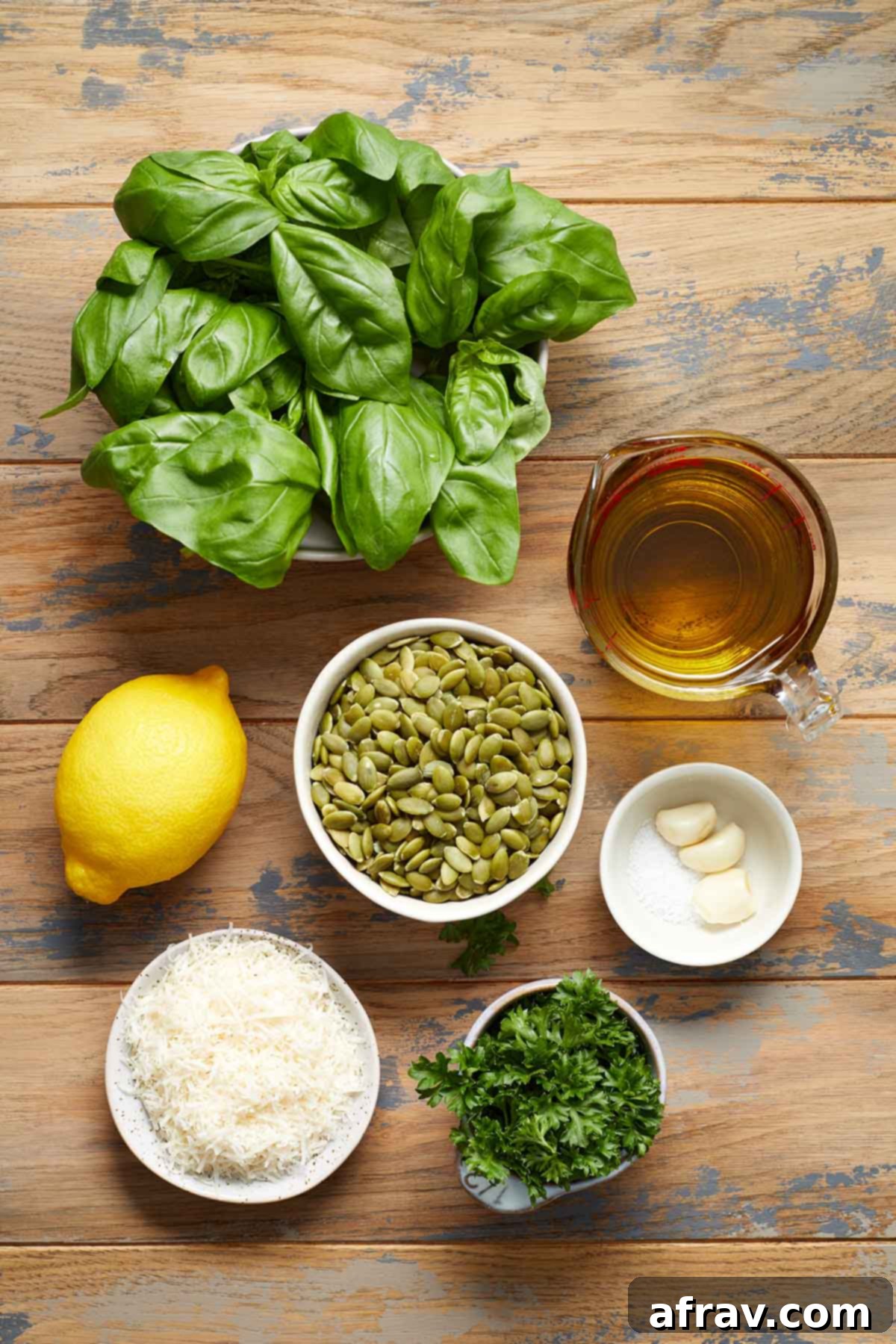 Various fresh ingredients like basil, pumpkin seeds, parmesan, lemon, and garlic arranged on a wooden table, ready for pumpkin seed pesto.