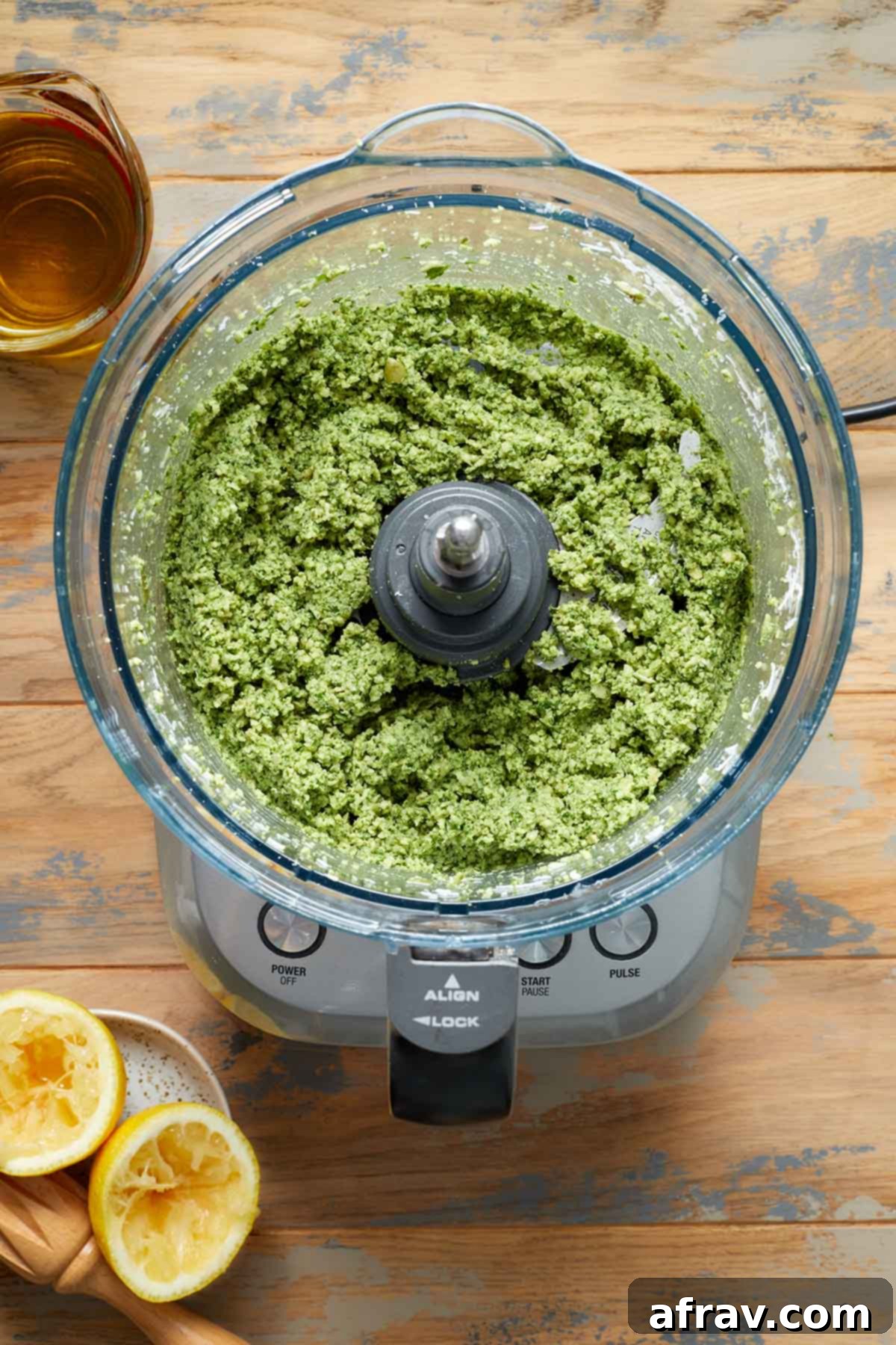 Pesto ingredients partially blended in a food processor, showing a coarse mixture of herbs and seeds.